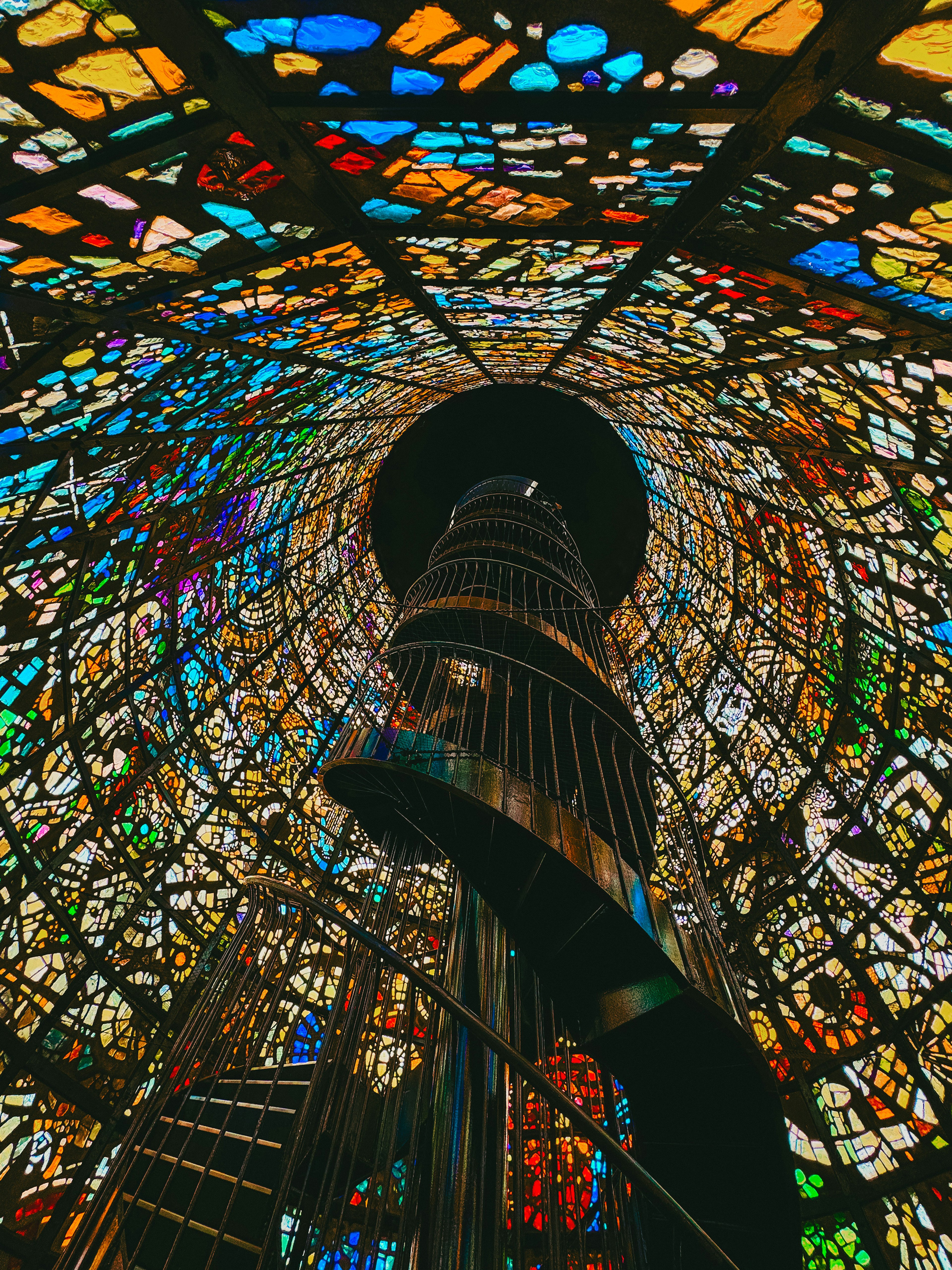 Interior of a spiral staircase with colorful stained glass ceiling