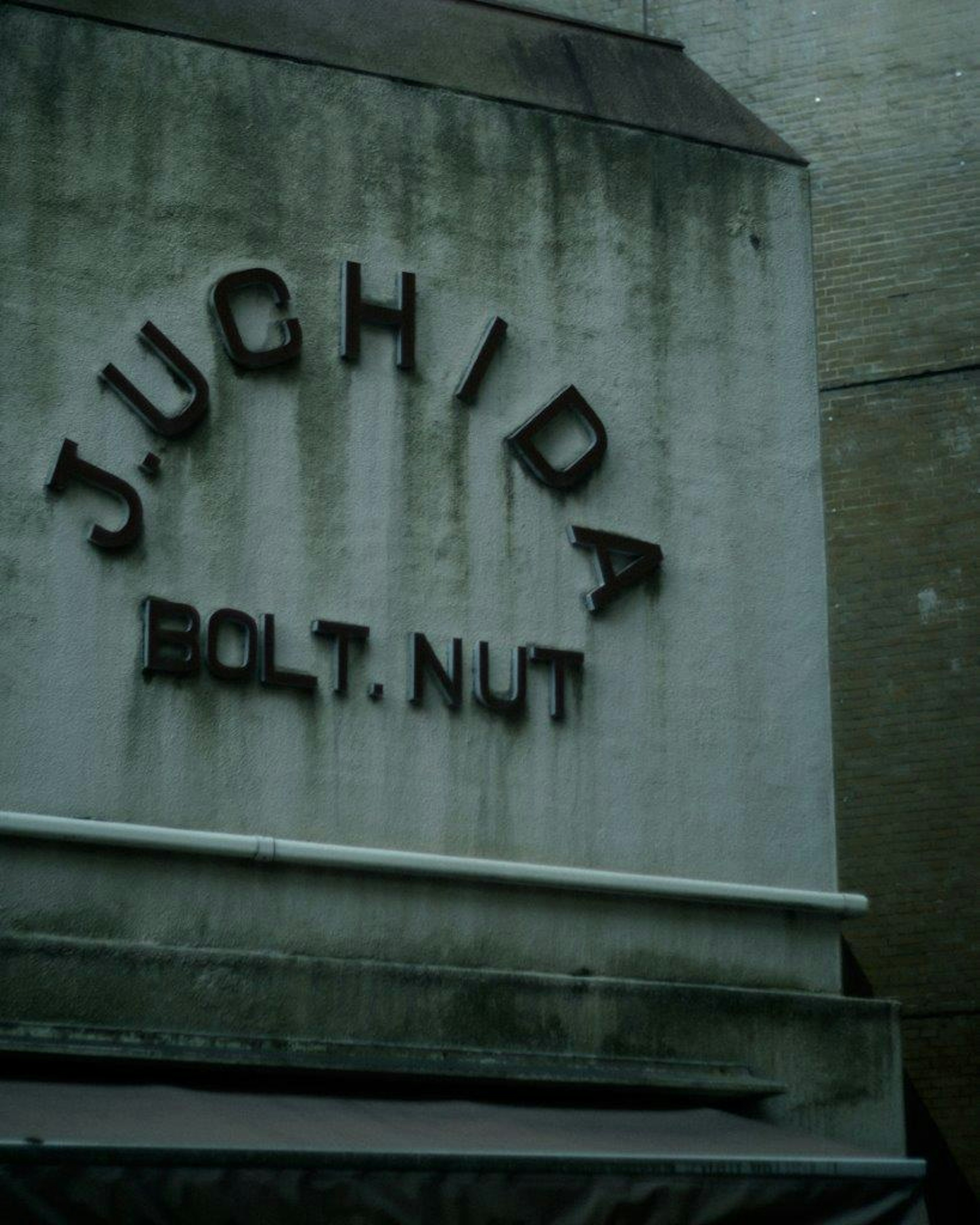 Cartel en el lado de un edificio que muestra J.UCHIDA y BOLT NUT