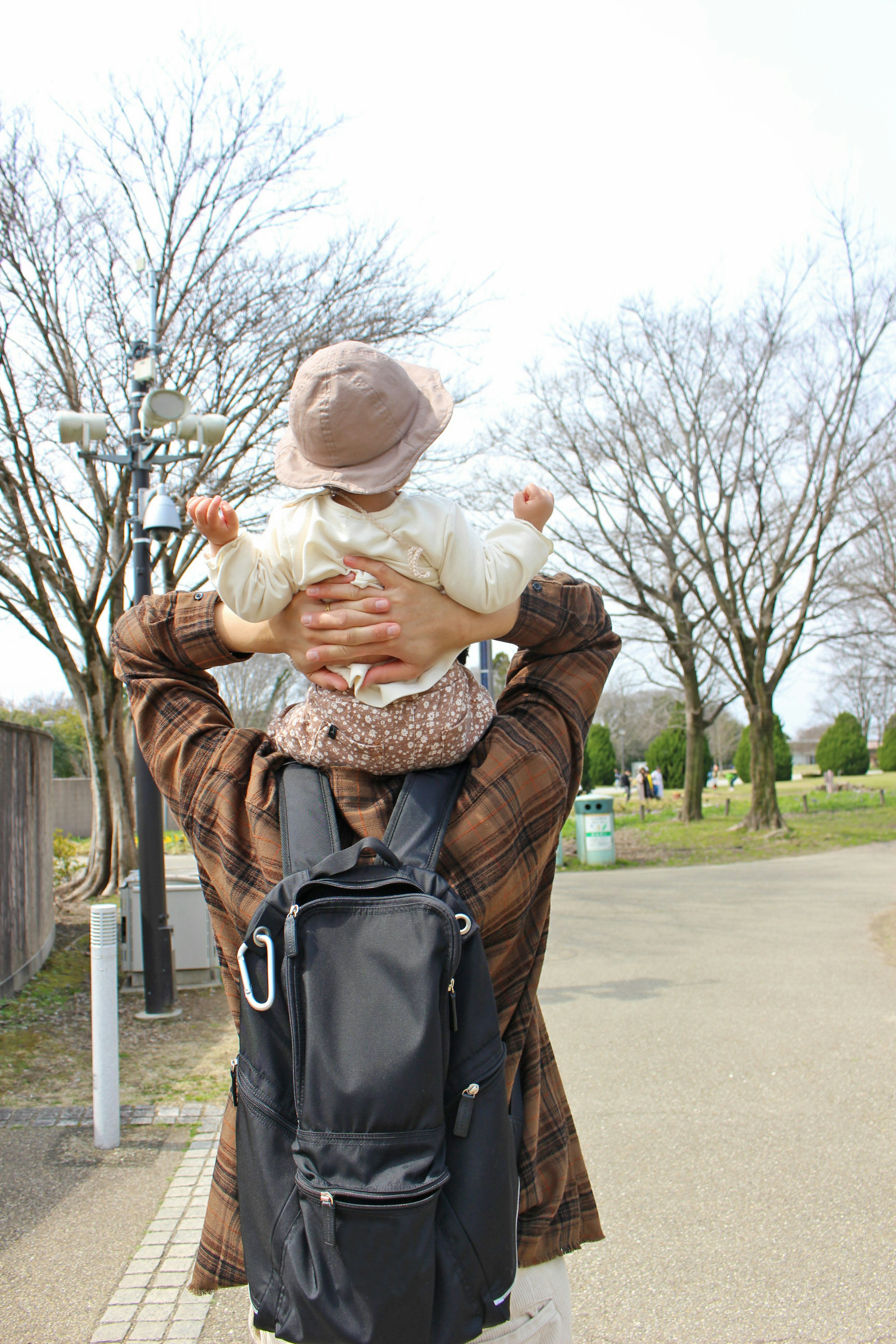 背中に子供を乗せた男性が公園を歩いている