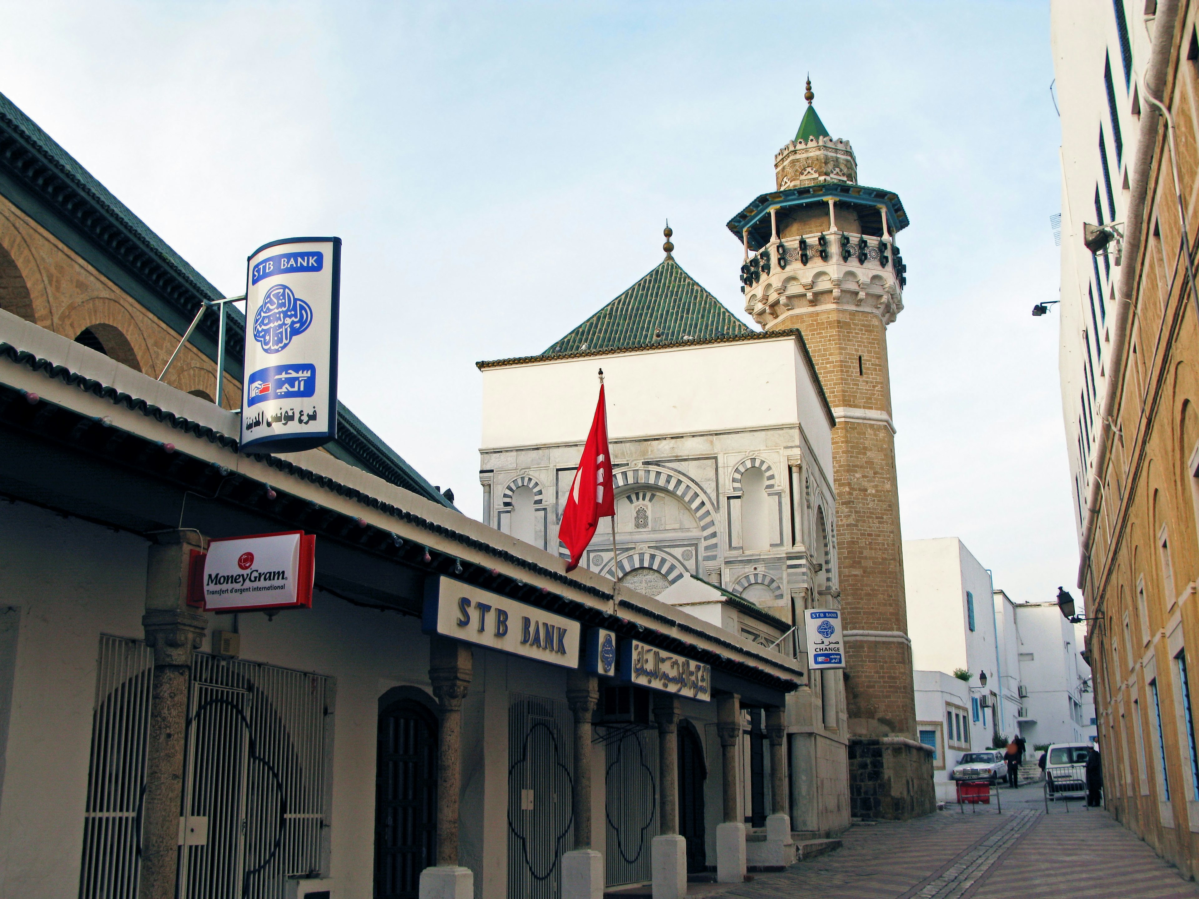 Street view featuring a mosque and tower with a red flag