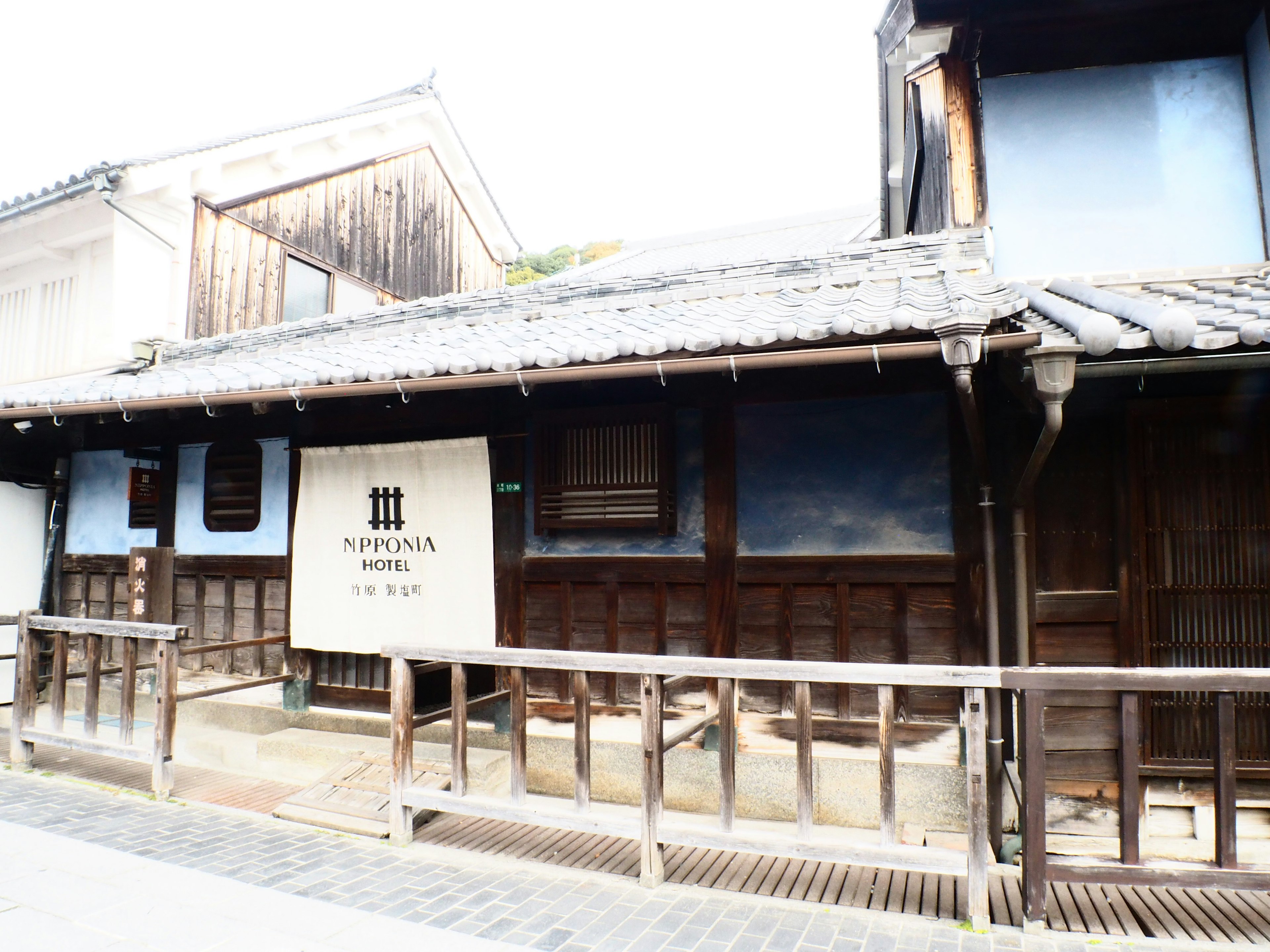 Traditional Japanese building exterior with wooden structure and blue wall sign at entrance