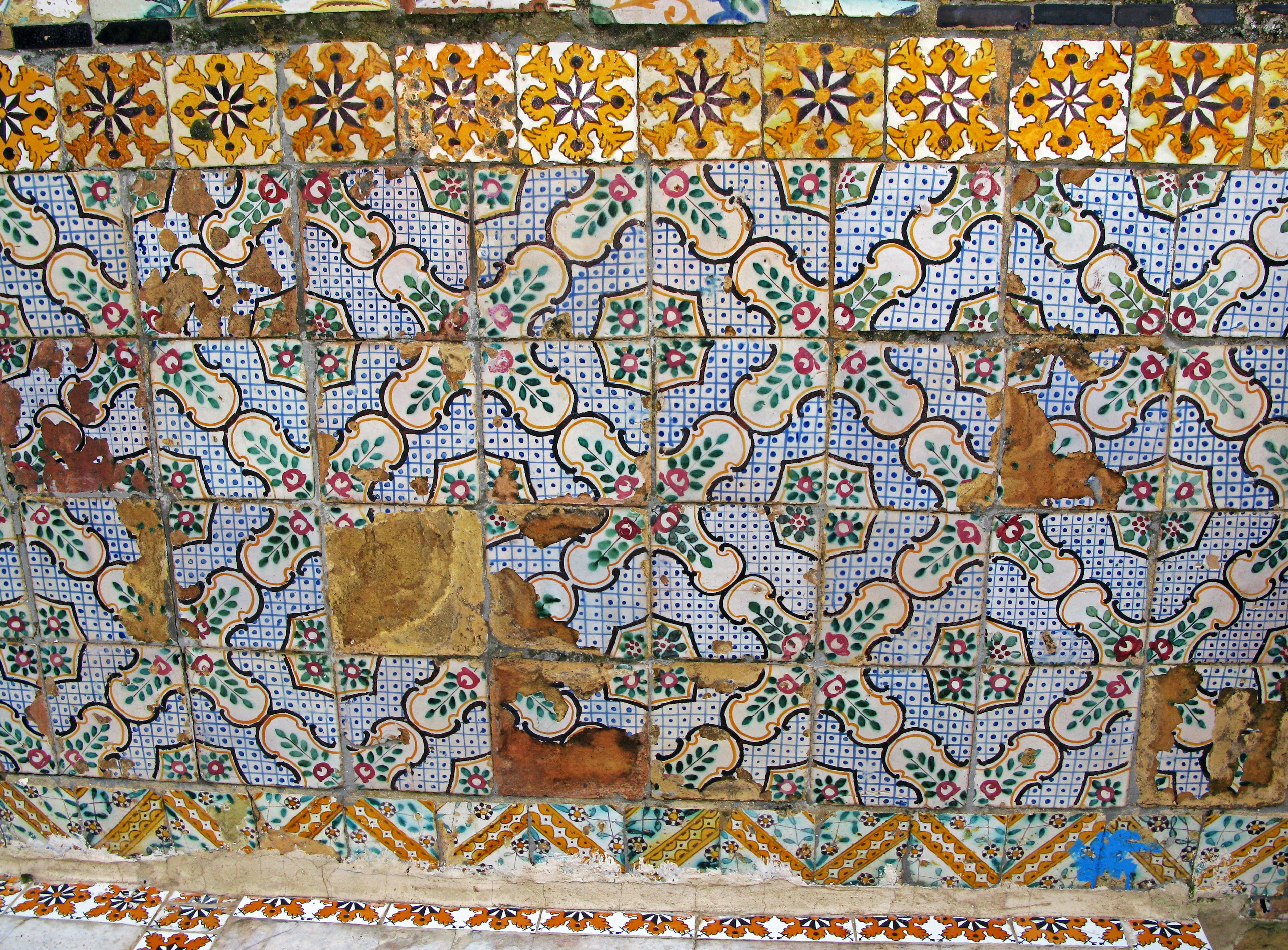 Decorative wall section with colorful tiles featuring classical patterns and signs of aging