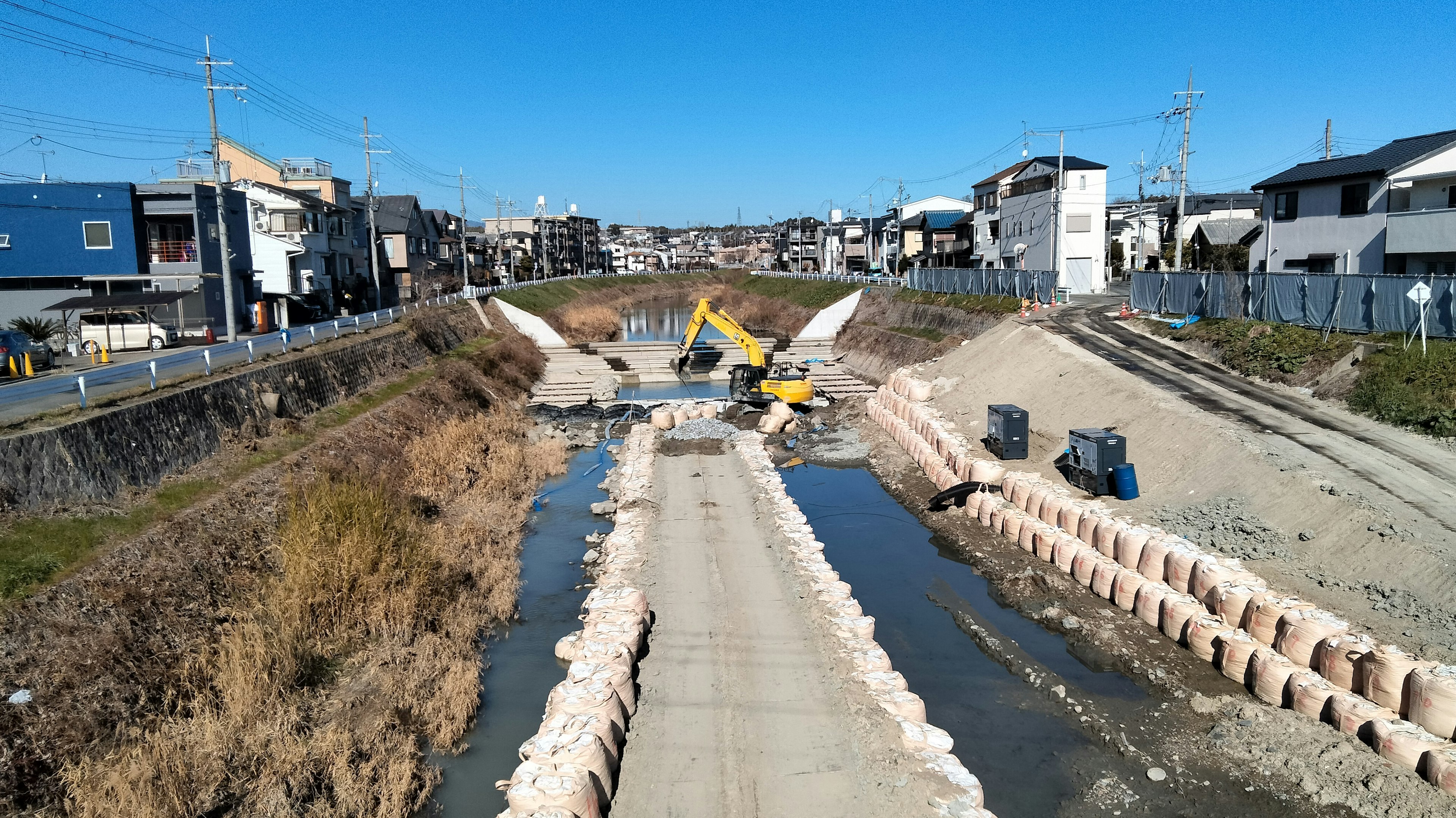 Site de construction le long d'une rivière avec des maisons environnantes visibles