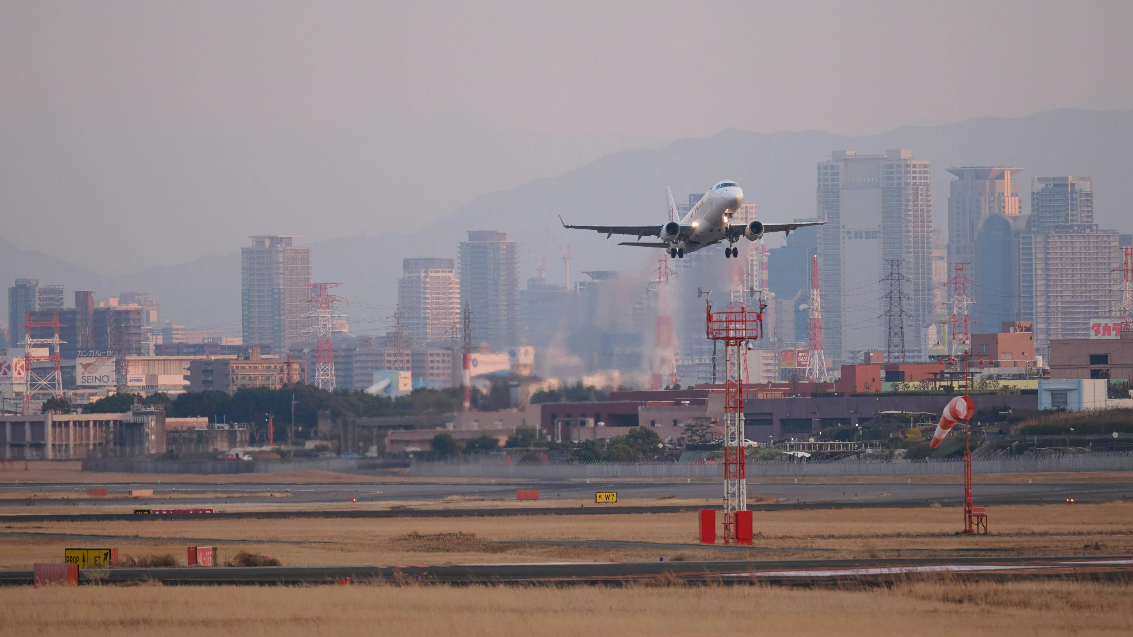 Aereo in atterraggio all'aeroporto con skyline della città sullo sfondo