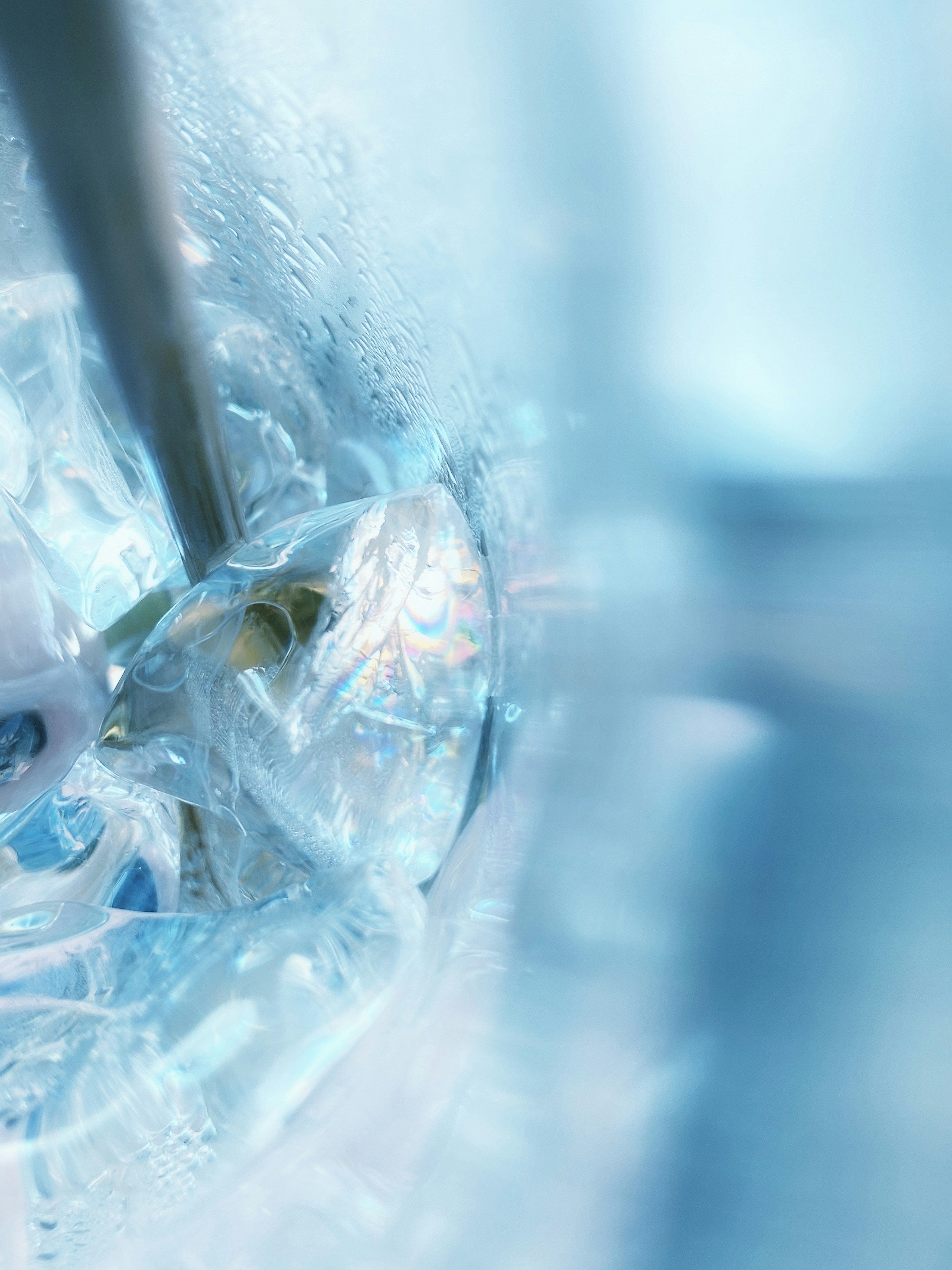 Close-up of a metallic straw in clear water with ice