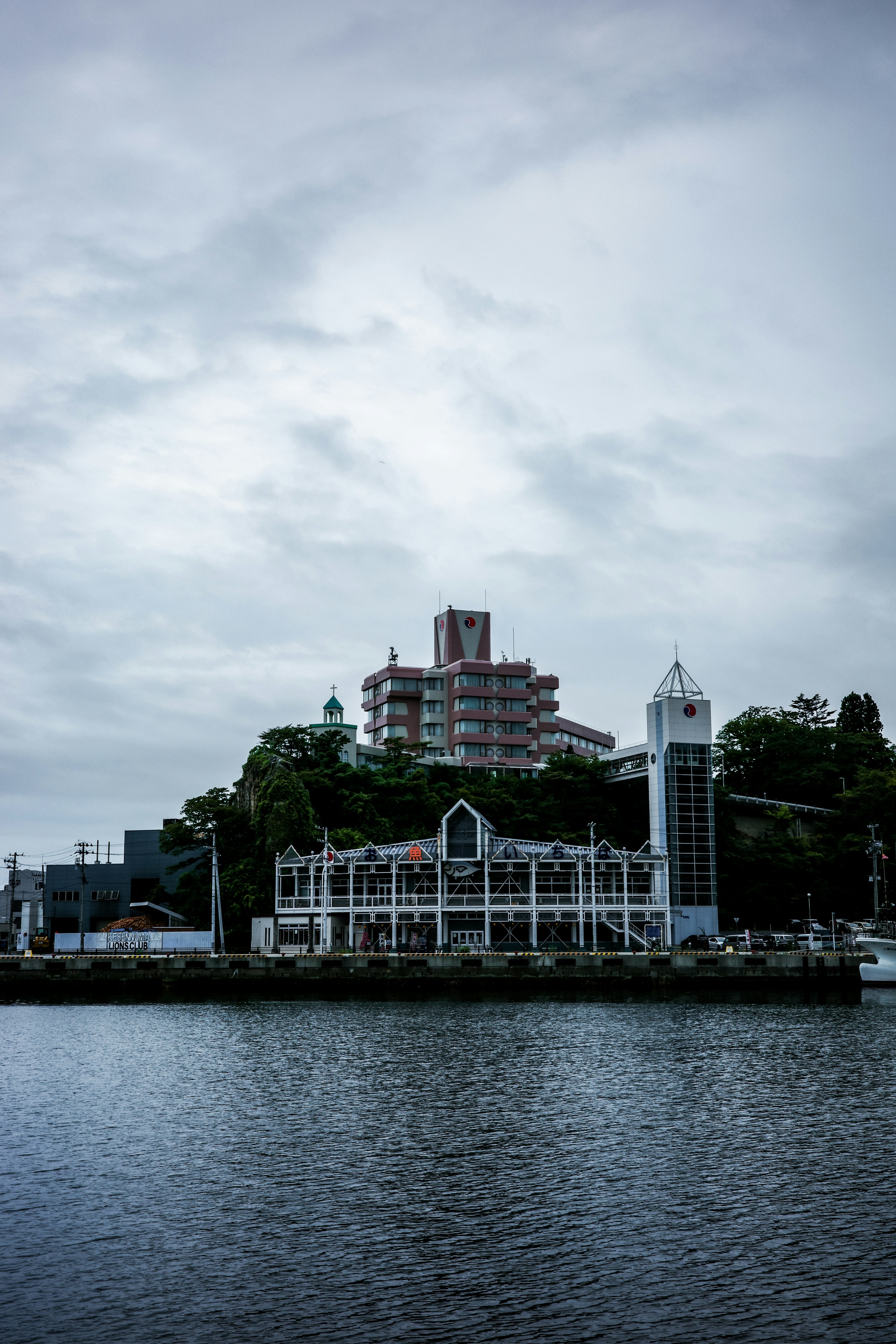 A cloudy sky over a waterfront with a white building and high-rise structures