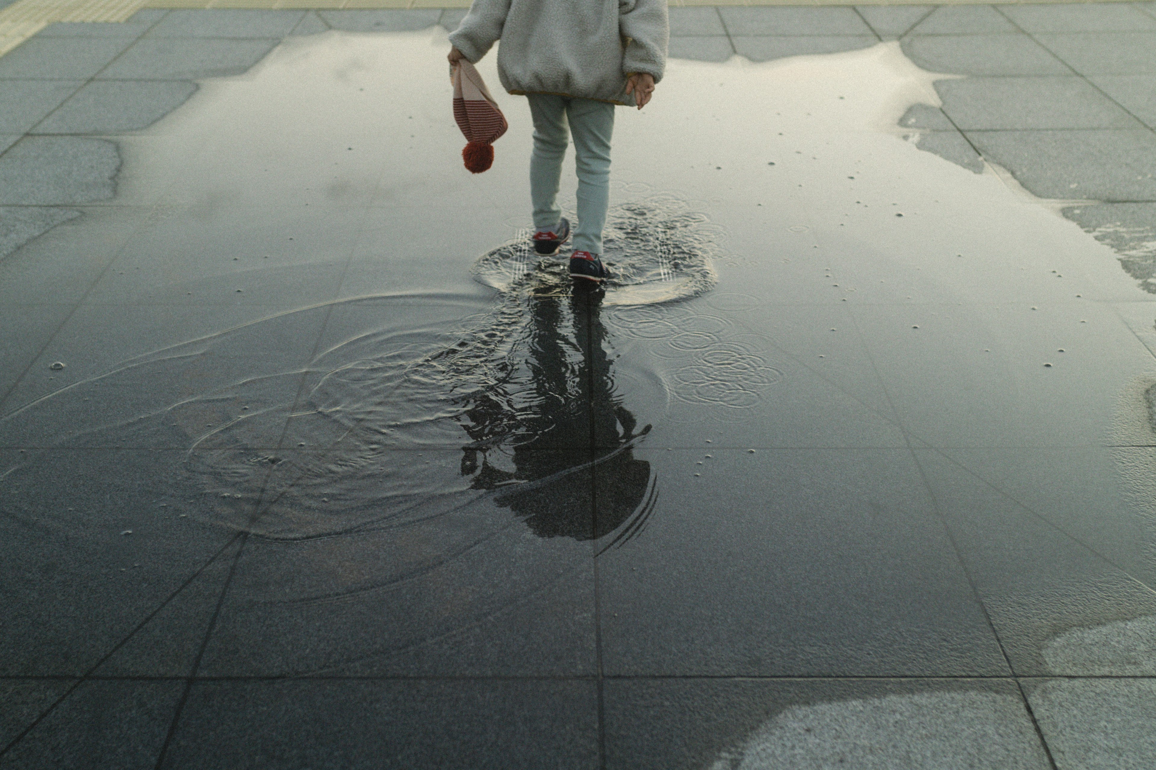 Enfant marchant dans une flaque d'eau créant des ondulations