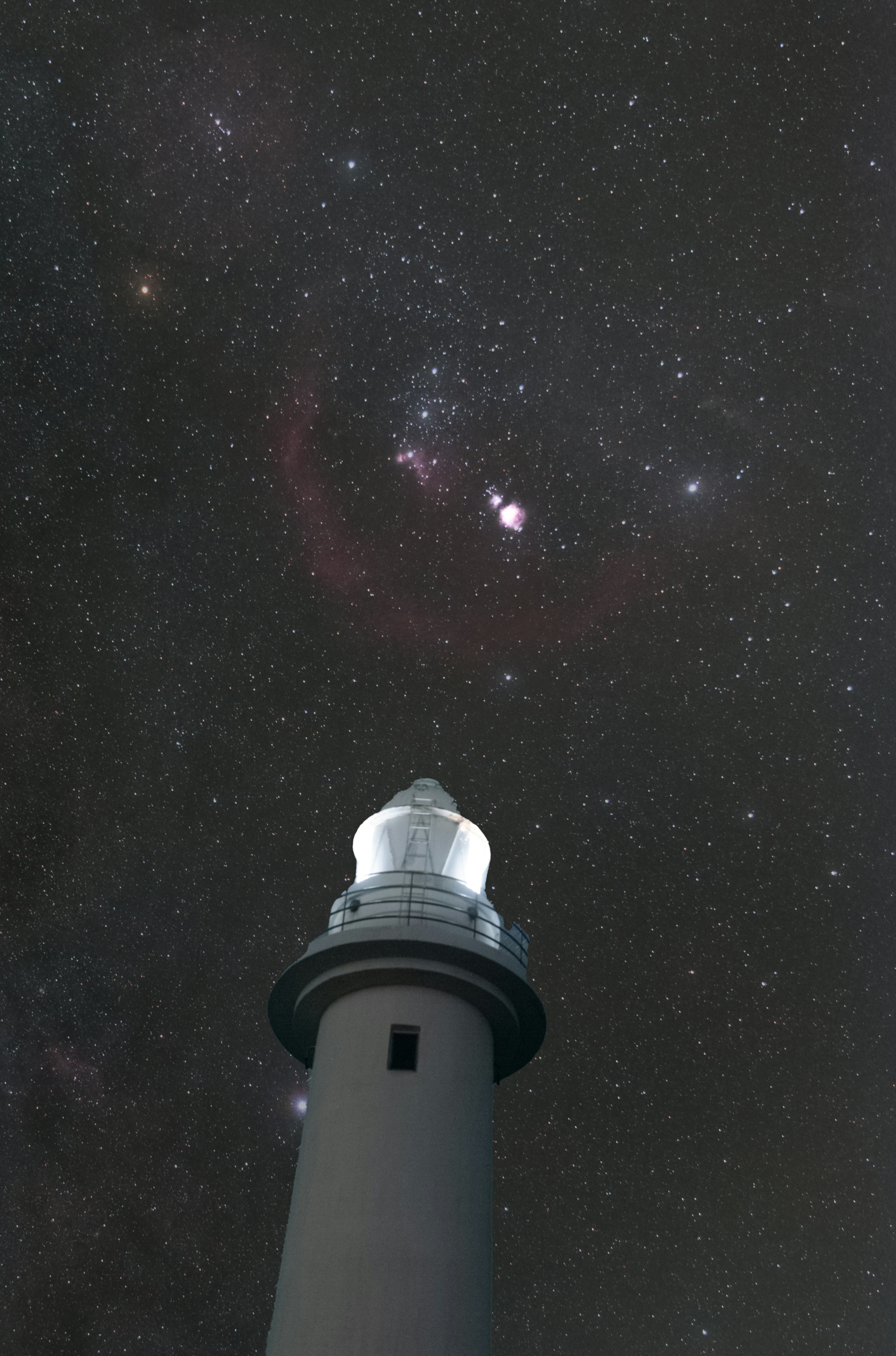 星空の下に立つ灯台の写真