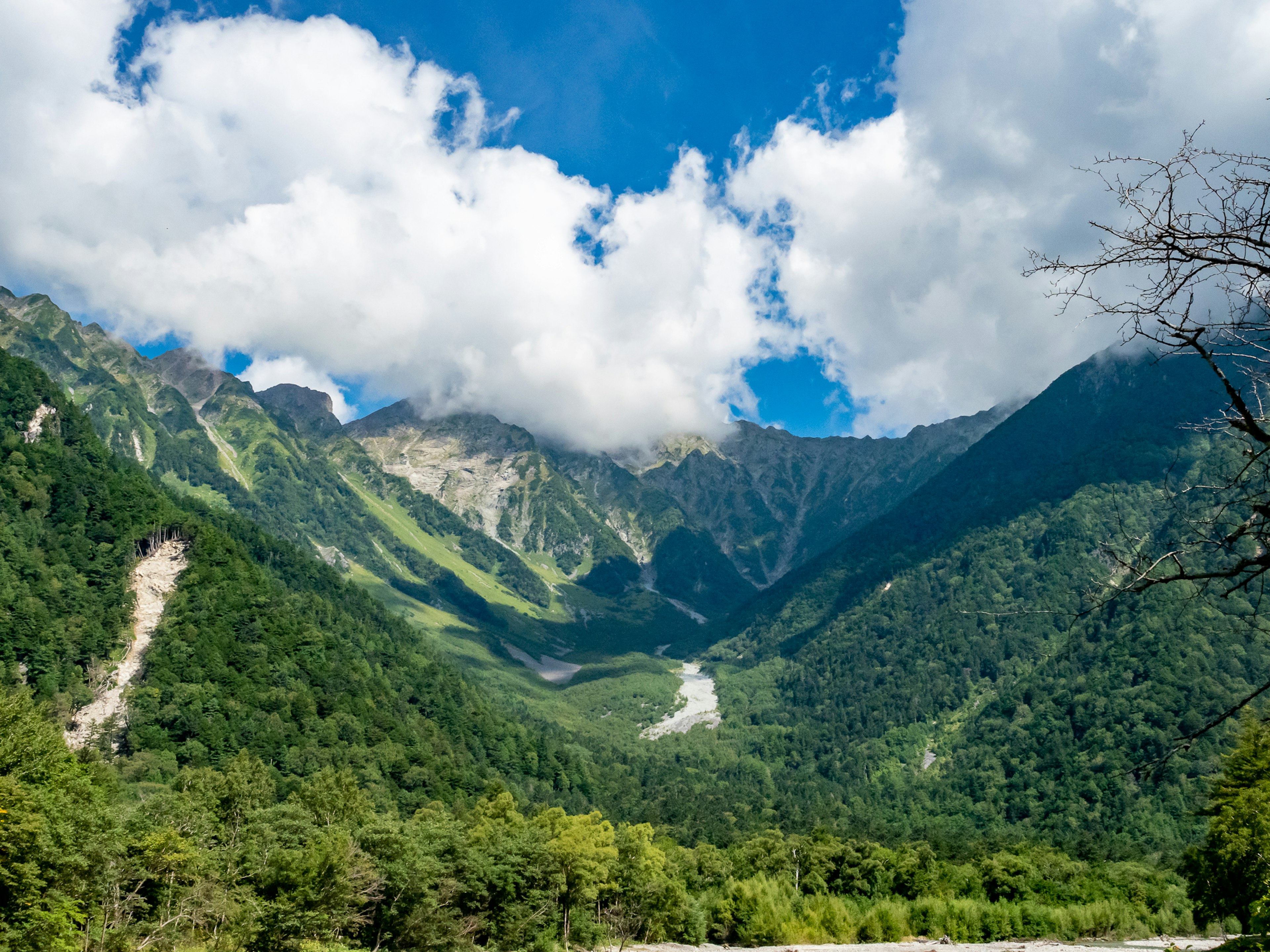 Montañas verdes bajo un cielo azul brillante con nubes blancas