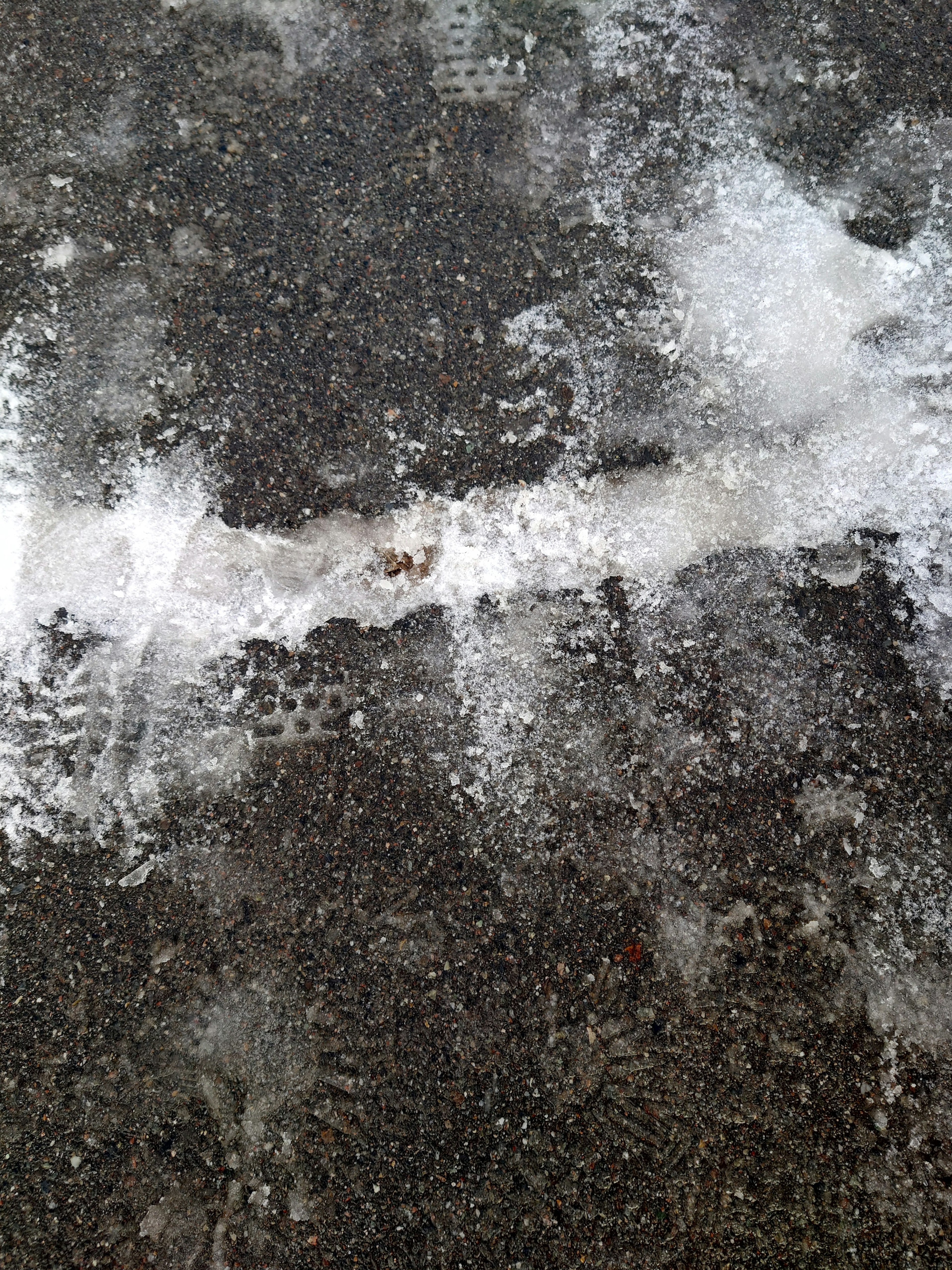 Black asphalt surface with ice patches and texture