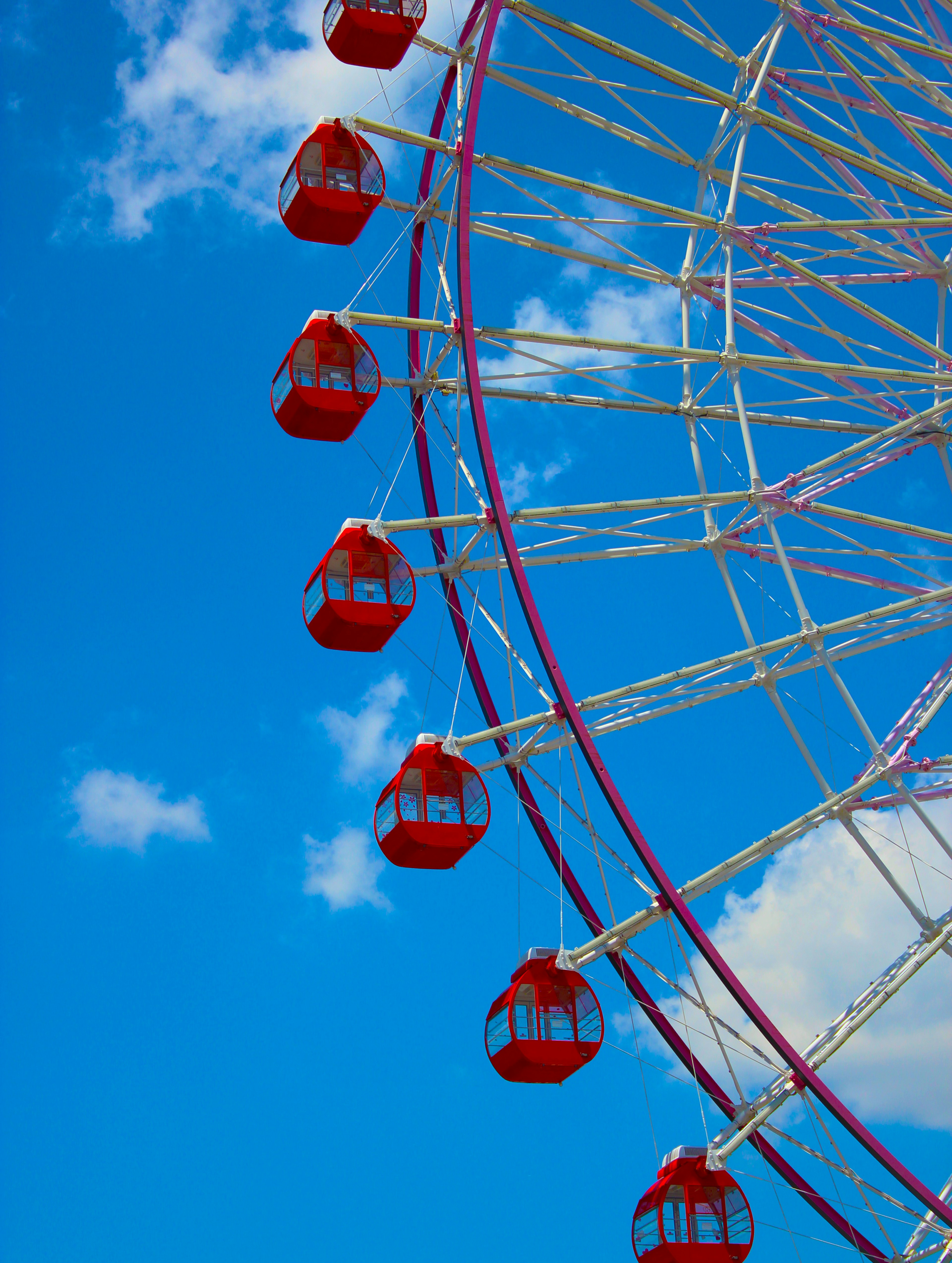 Vue partielle d'une grande roue avec des gondoles rouges sur fond de ciel bleu