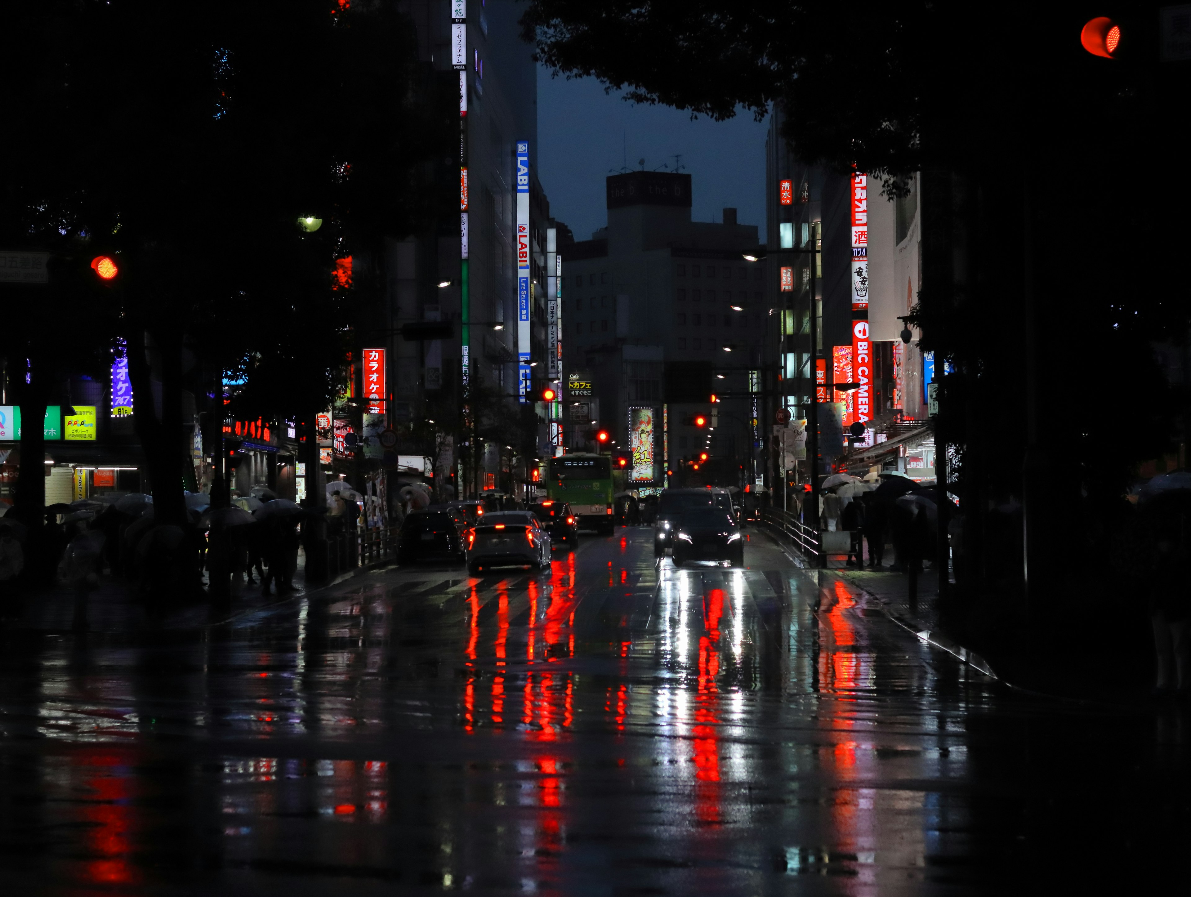 夜の街並みに映る赤い光の反射と雨に濡れた道路