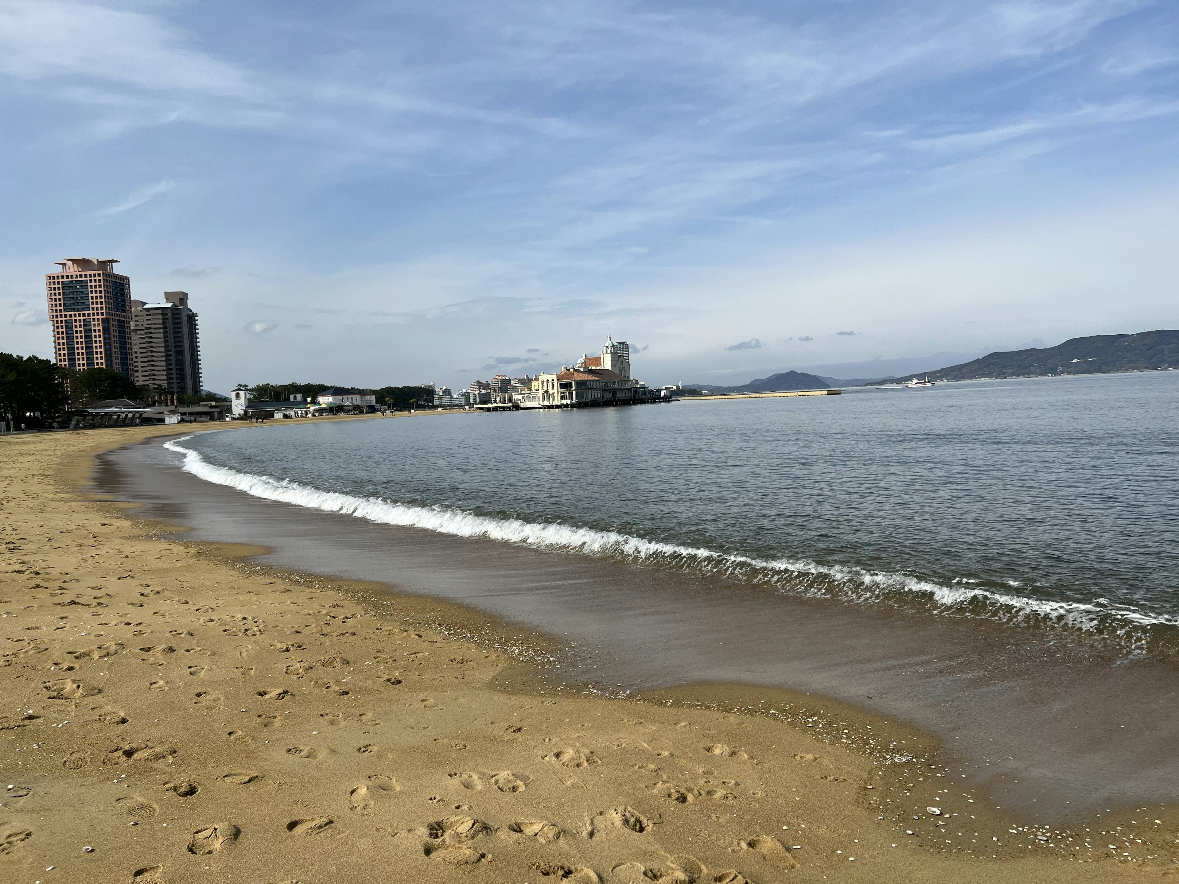 Escena de playa con olas suaves y edificios altos al fondo