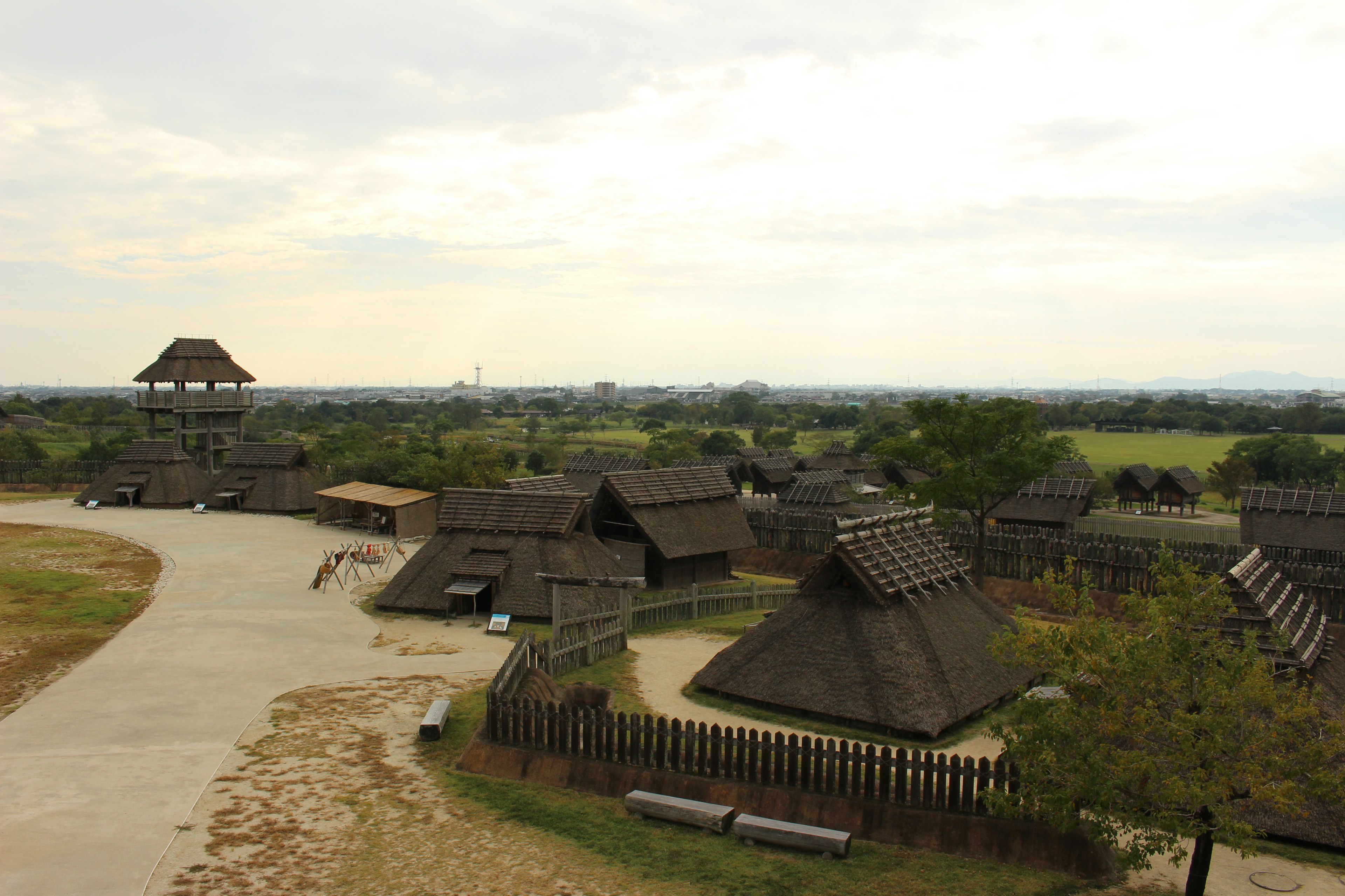 A historical village scene with thatched houses and a watchtower