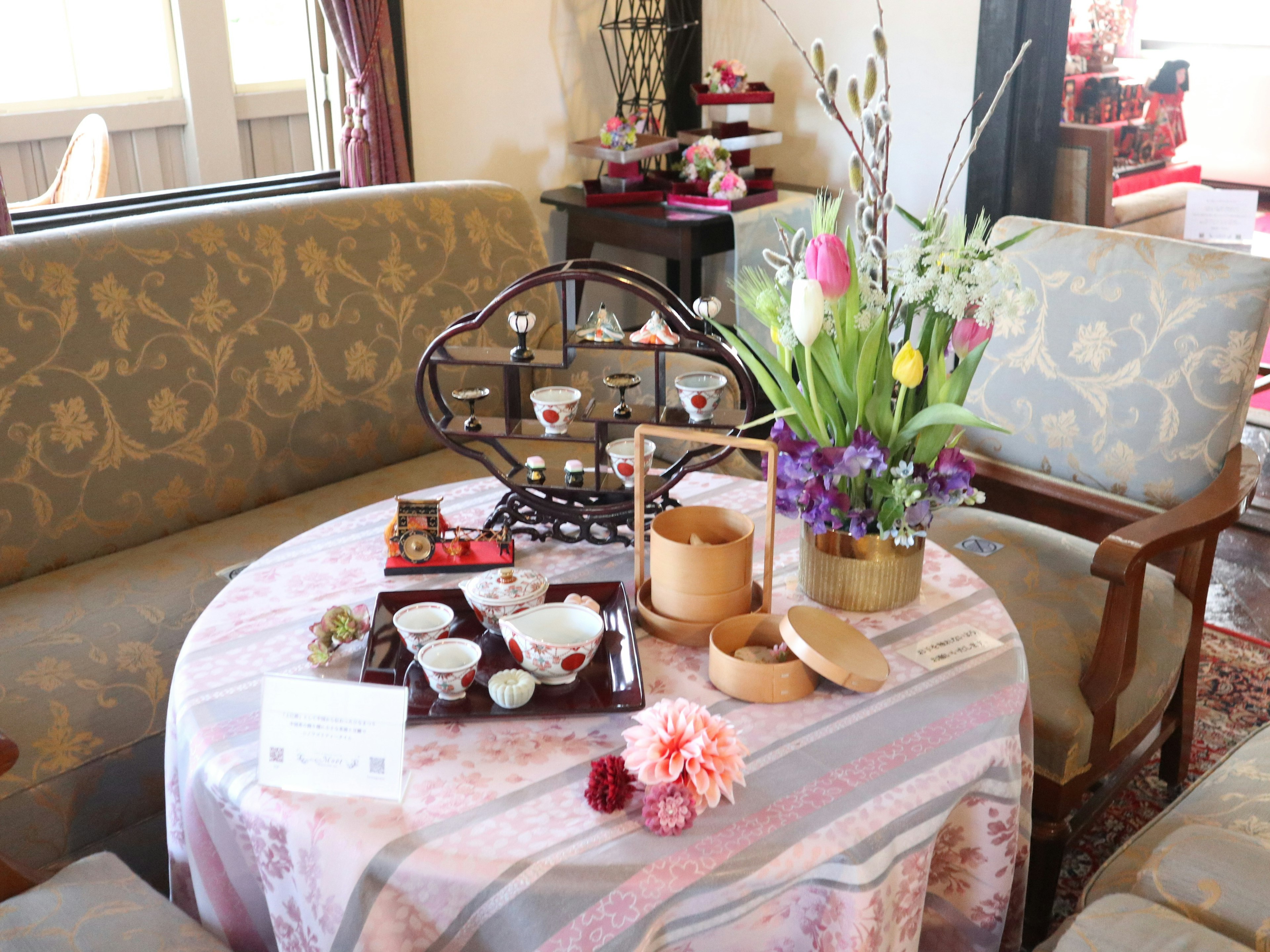 Cozy seating area with a tea set and floral arrangement on a round table