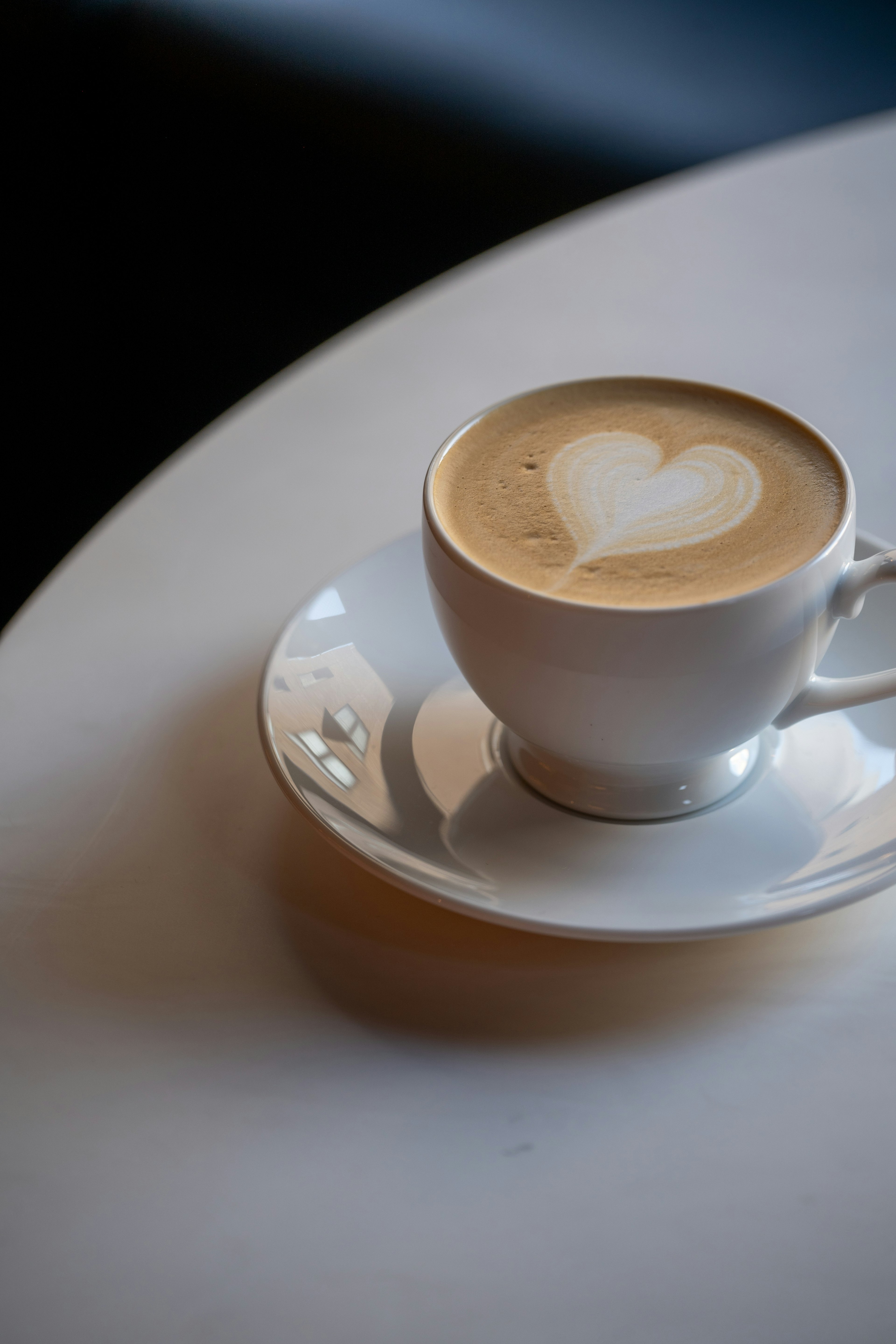 Kopi dalam cangkir putih dengan seni latte berbentuk hati