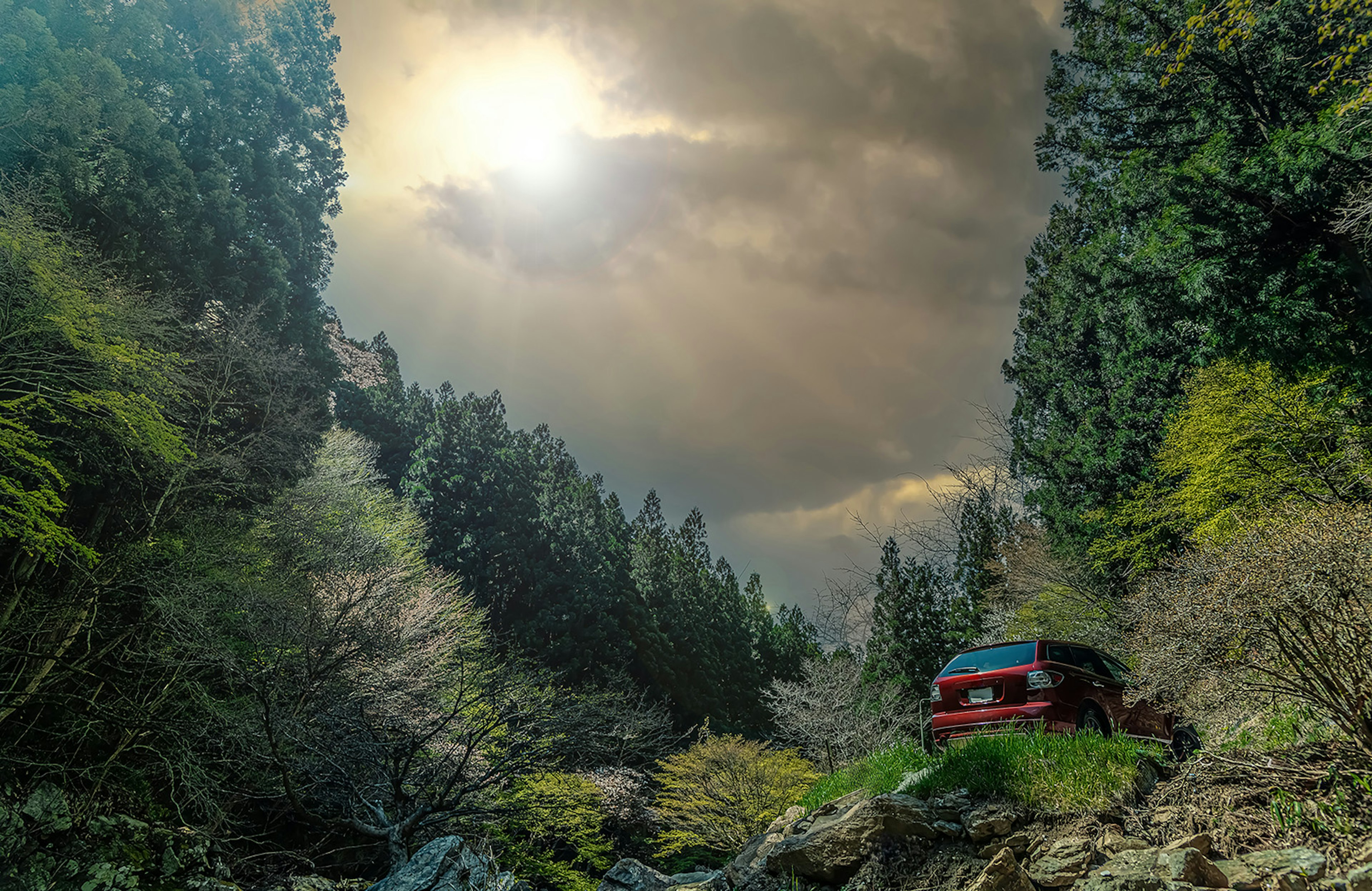 Un coche rojo estacionado en un paisaje verde bajo un cielo nublado