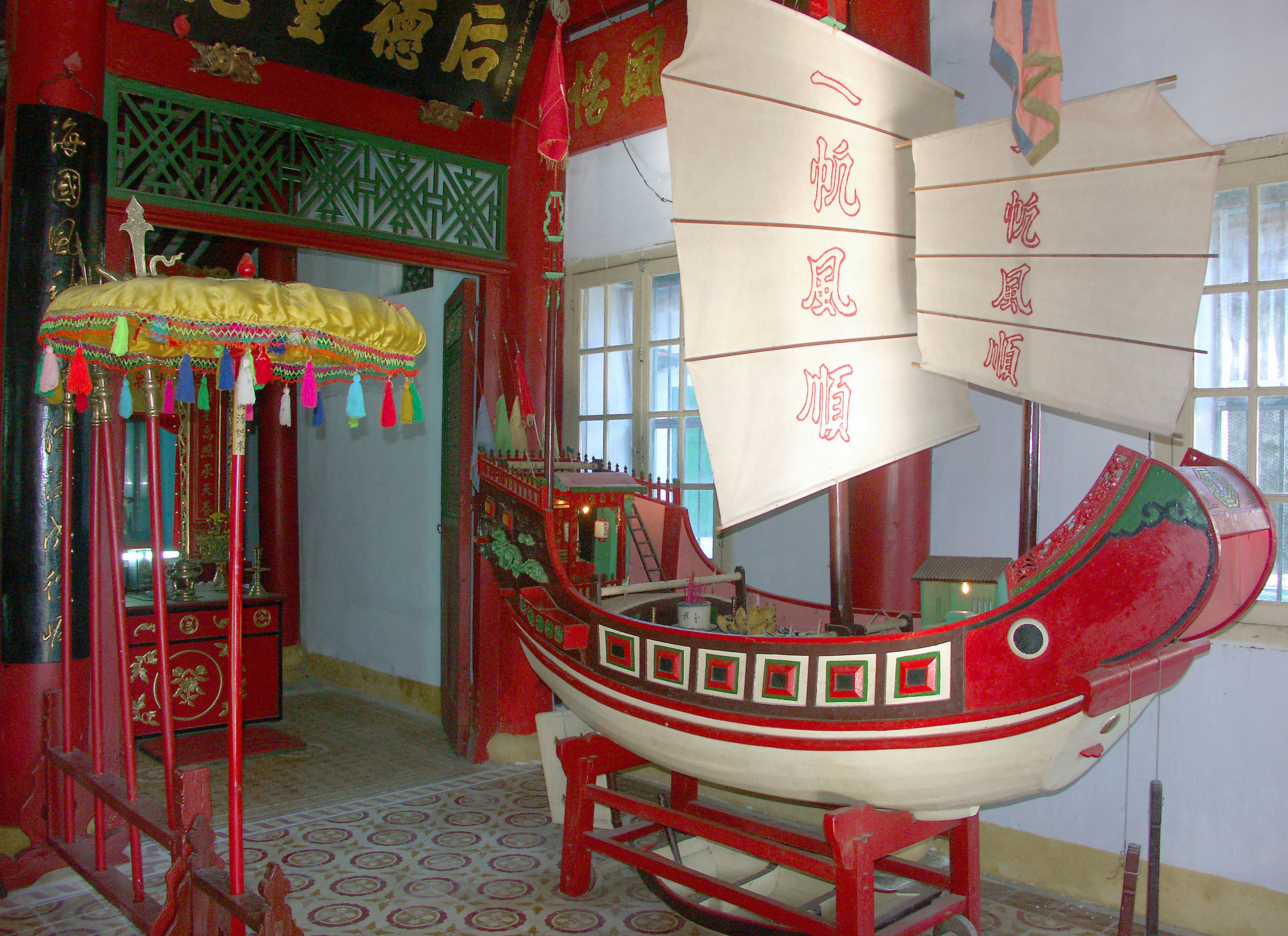 Interior of a traditional building featuring a red boat with sails and decorative elements