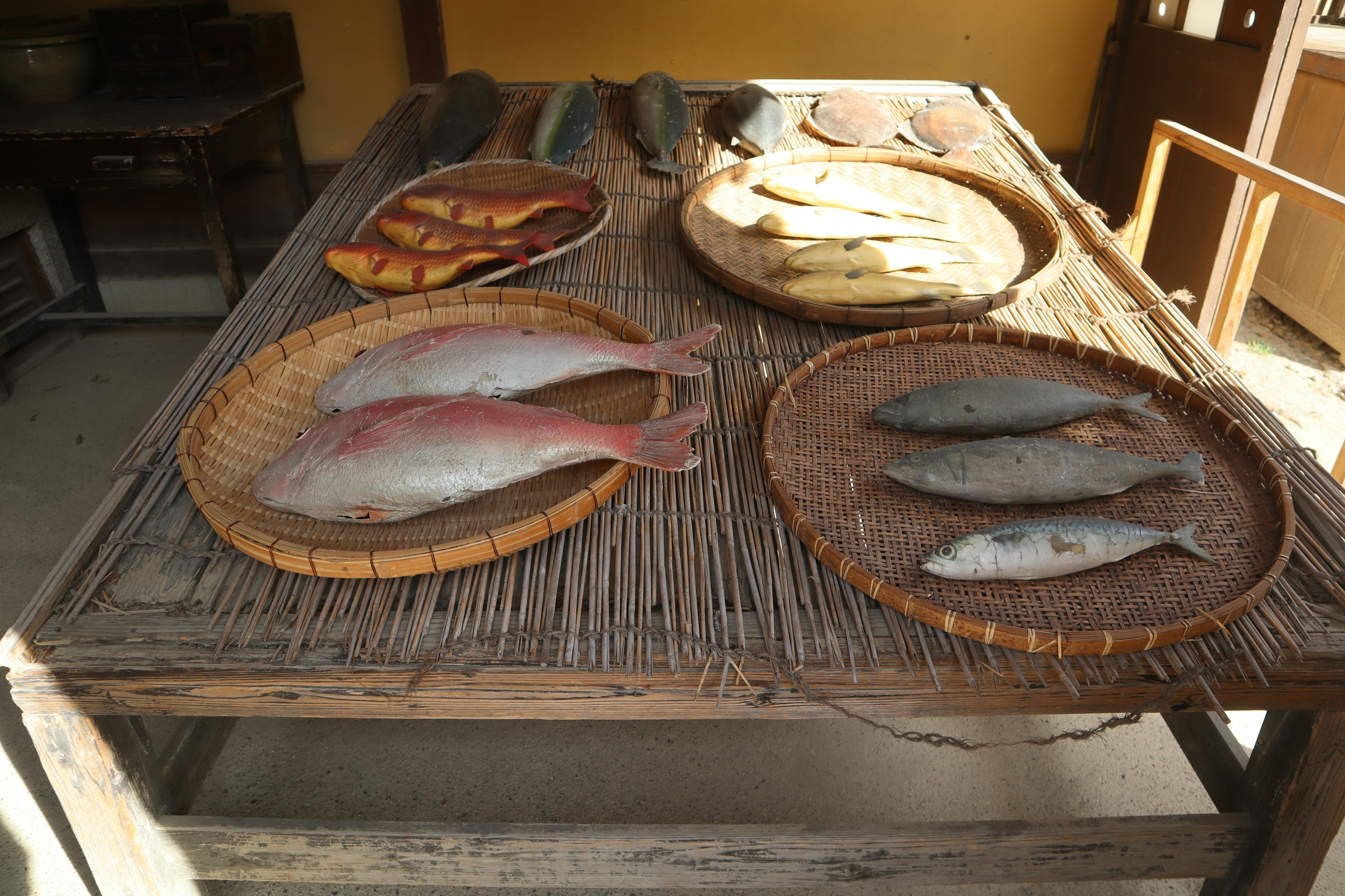 Varios peces exhibidos en cestas tejidas sobre una mesa de madera