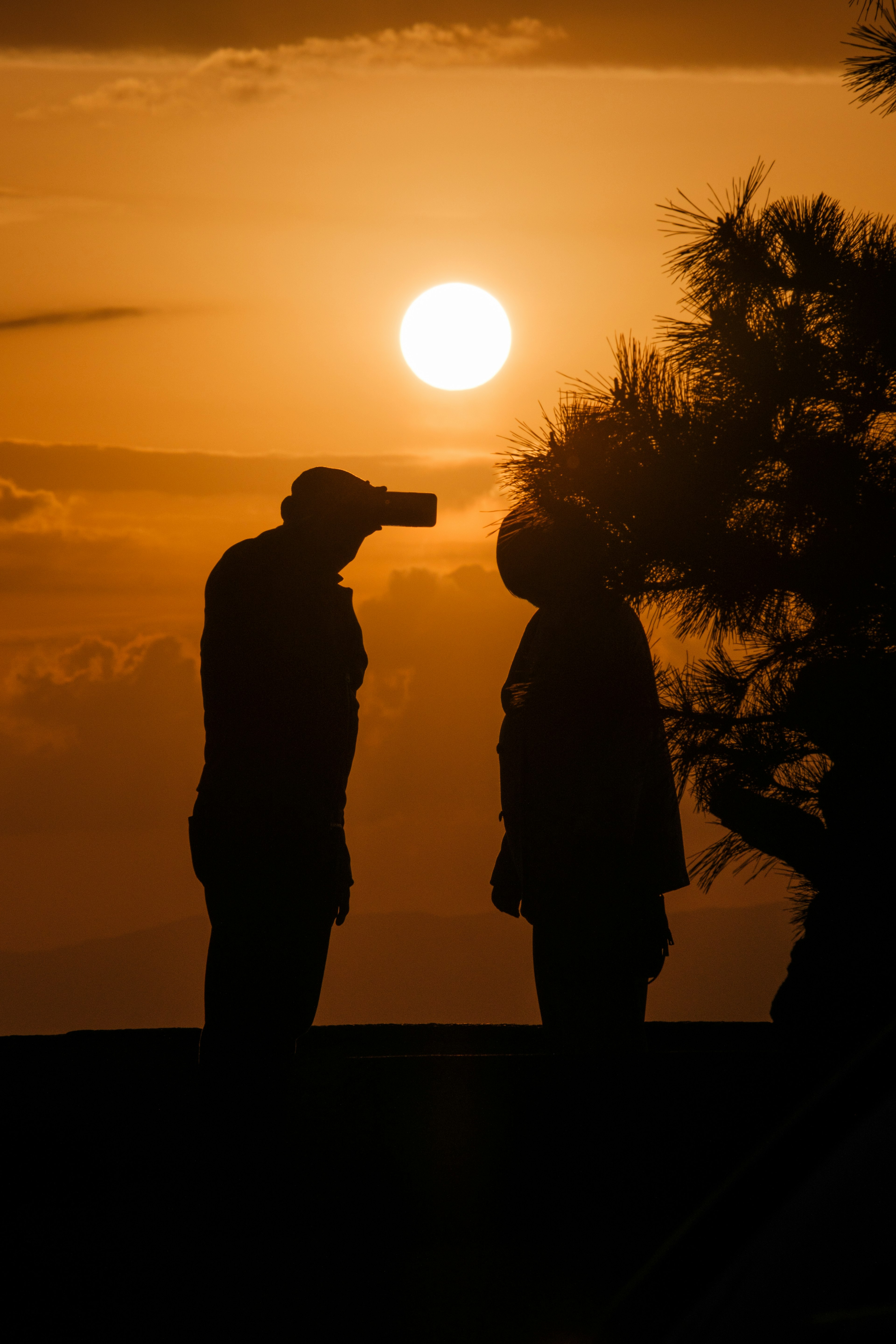 Silhouettes of two people conversing against a sunset backdrop