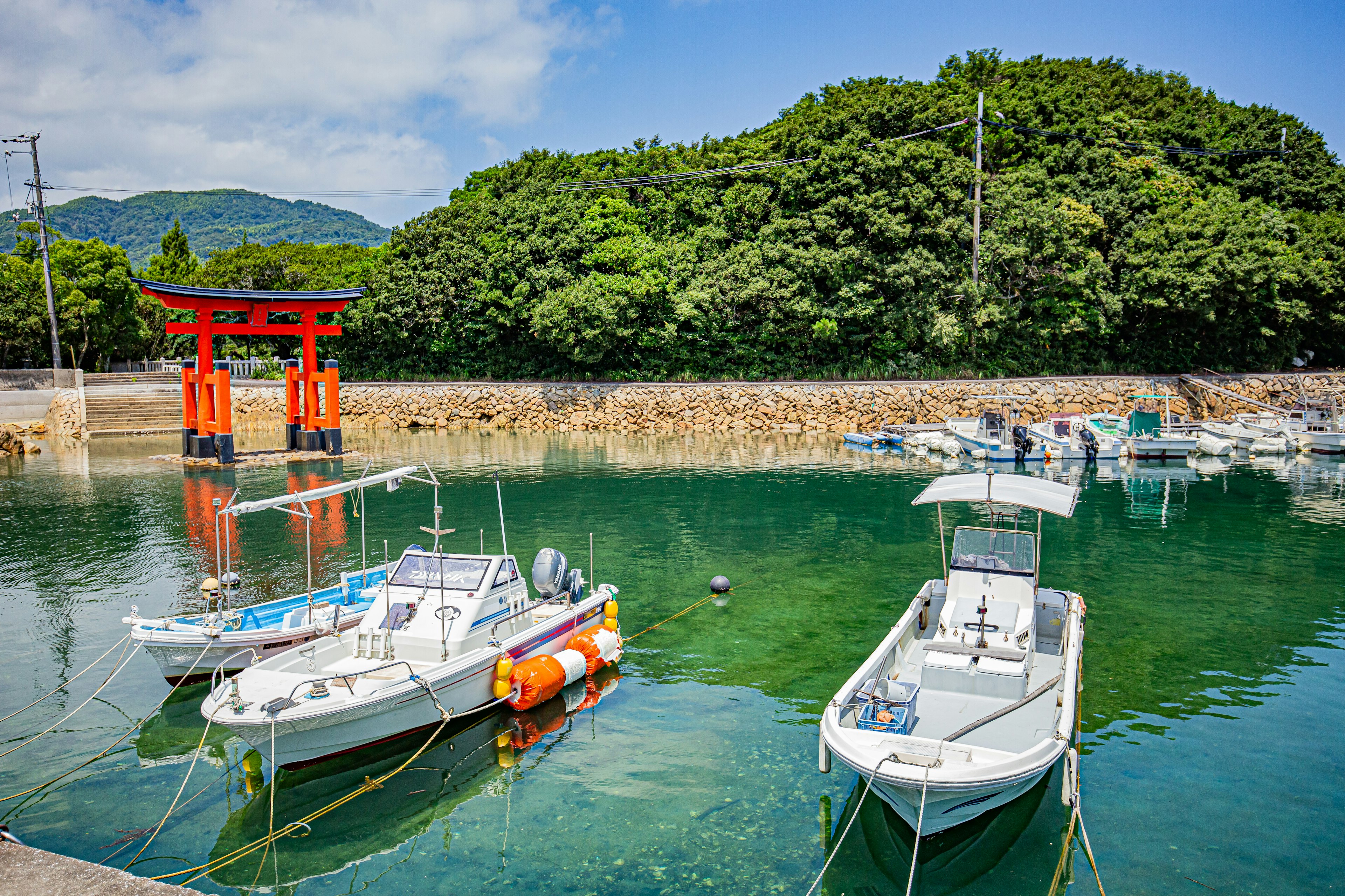 静かな港に浮かぶ小さなボートと赤い鳥居のある風景