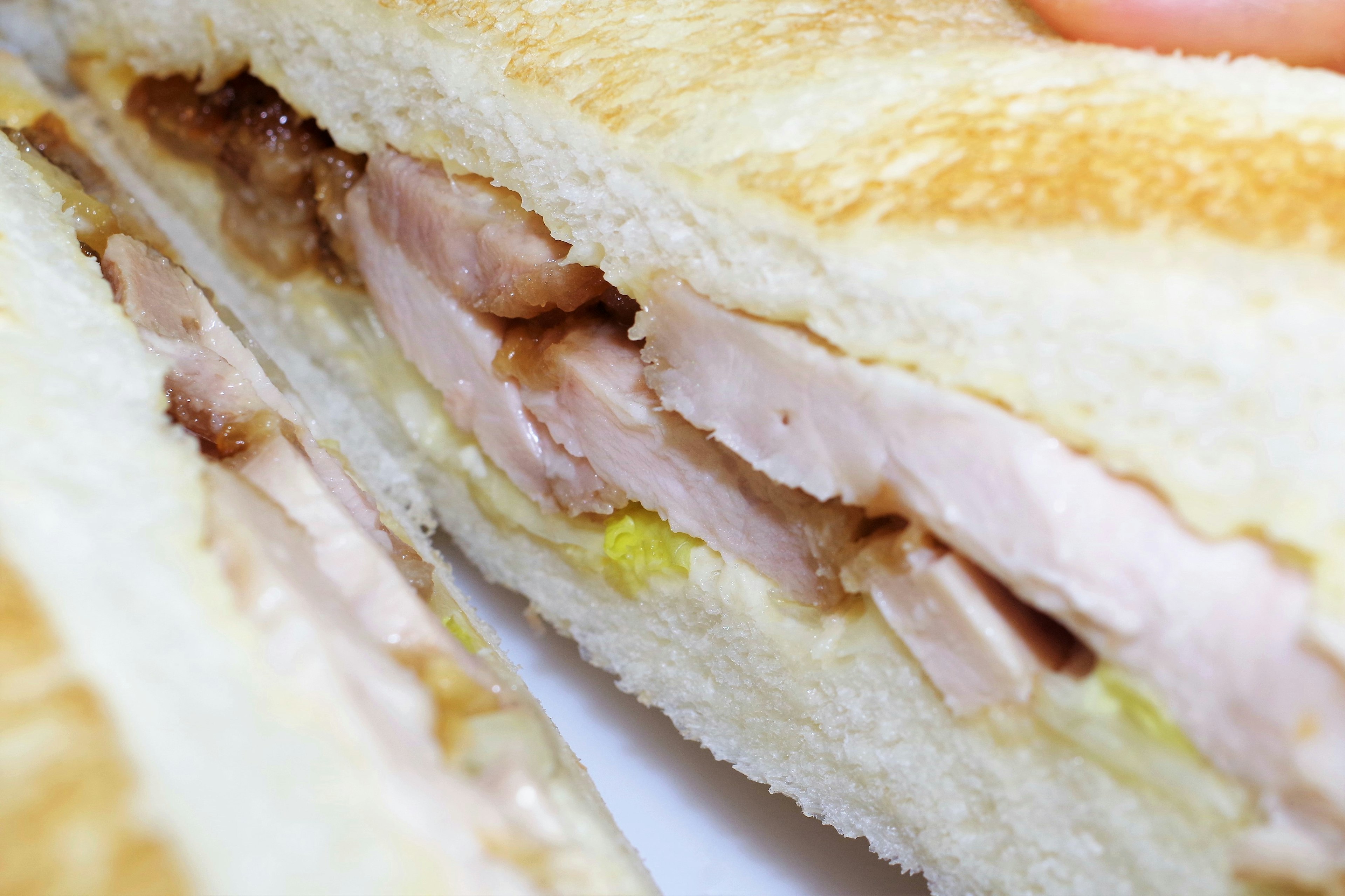 Ein Sandwich mit geschnittenem Hühnchen und Gurken zwischen geröstetem Brot