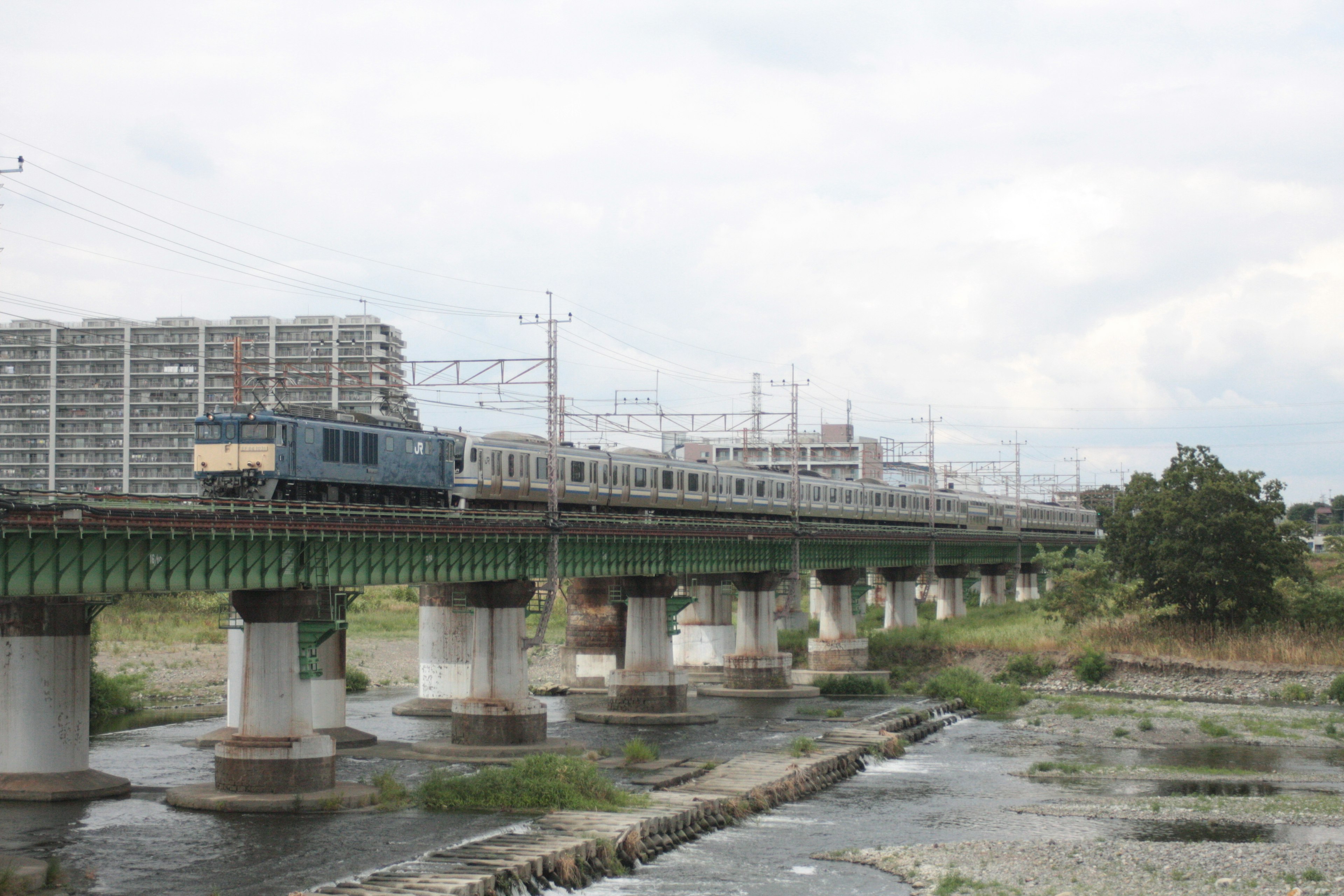 青い電車が川を渡る橋を走る風景