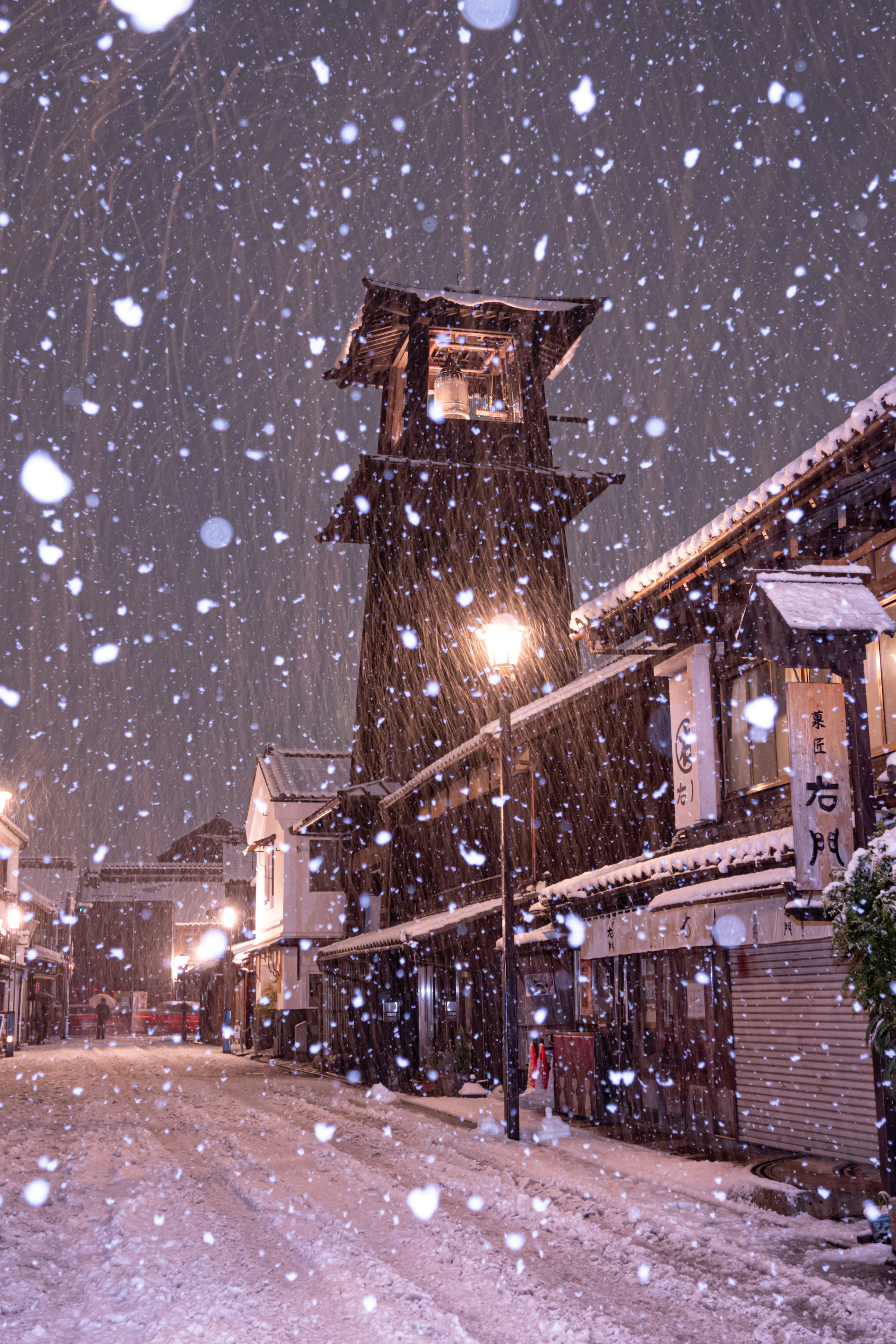 Scenario notturno di una torre dell'orologio in una strada innevata