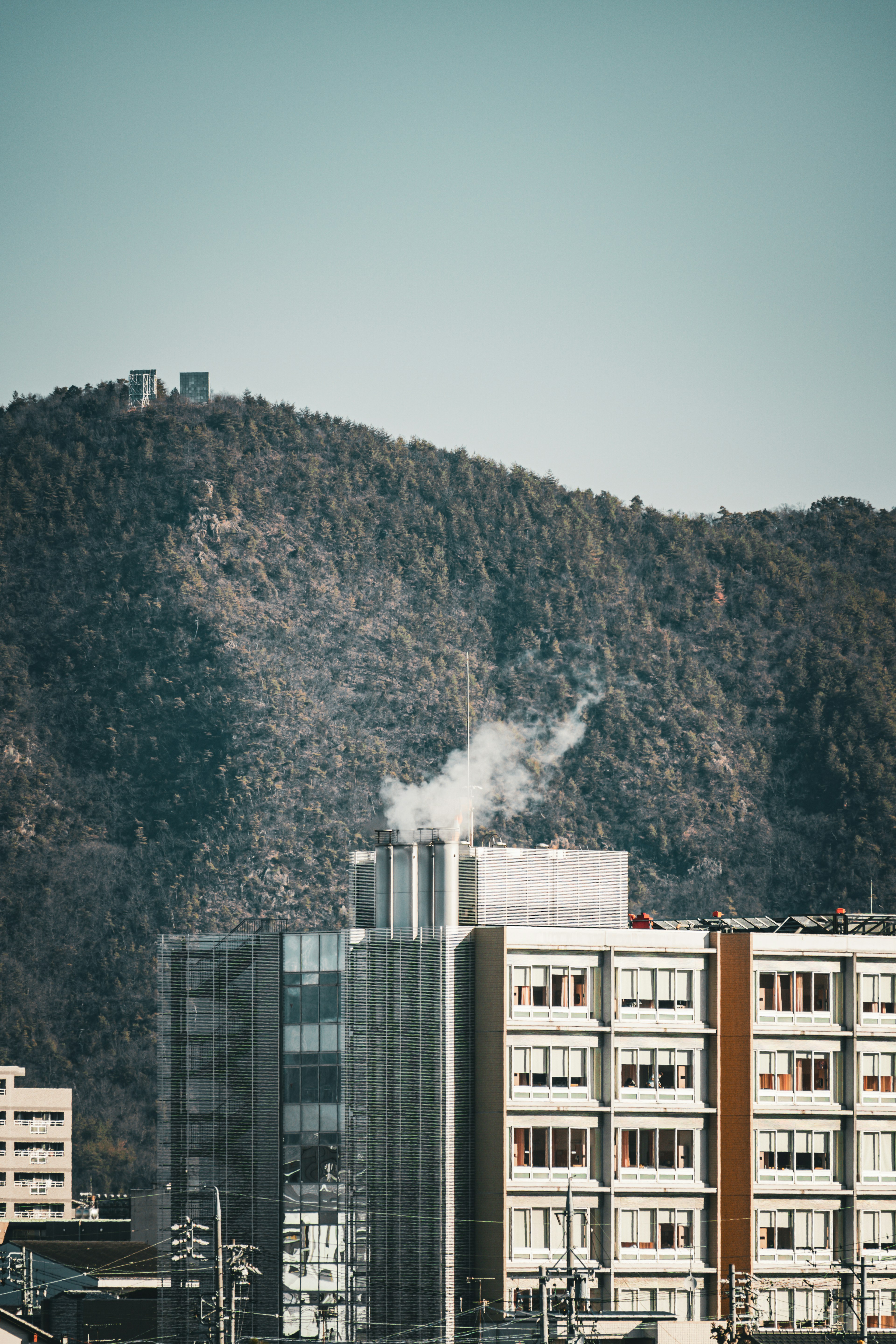 Scena urbana con un edificio che emette fumi e una montagna sullo sfondo