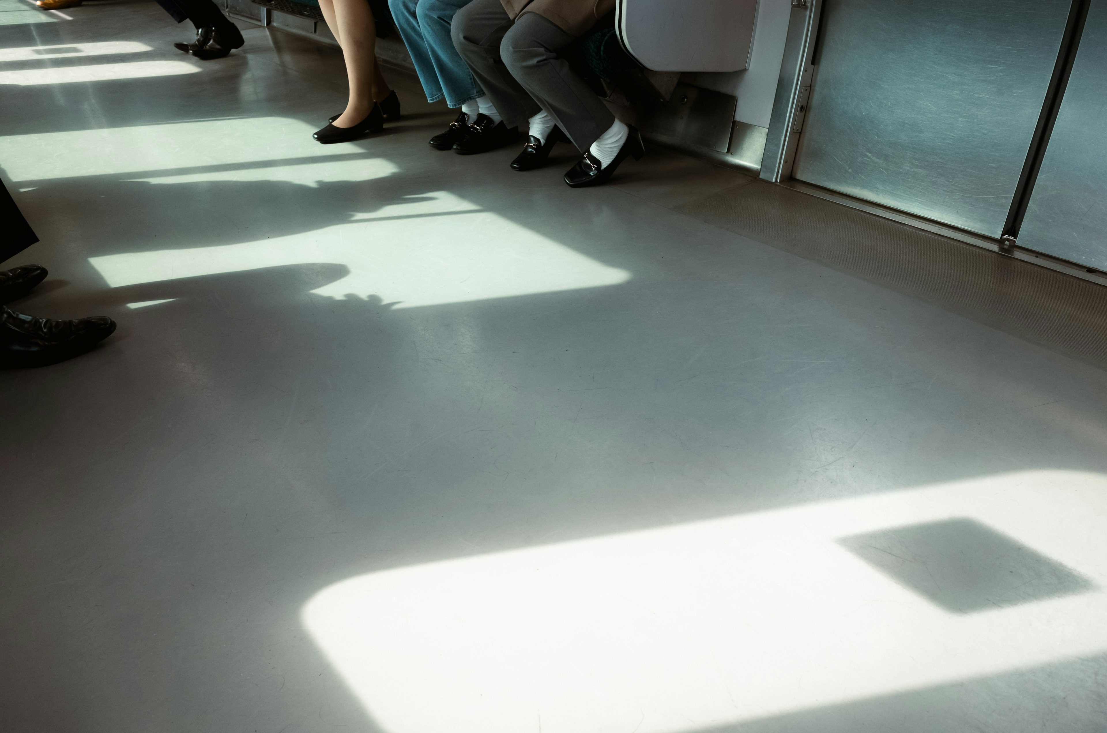 Feet and shadows of people sitting in a subway car