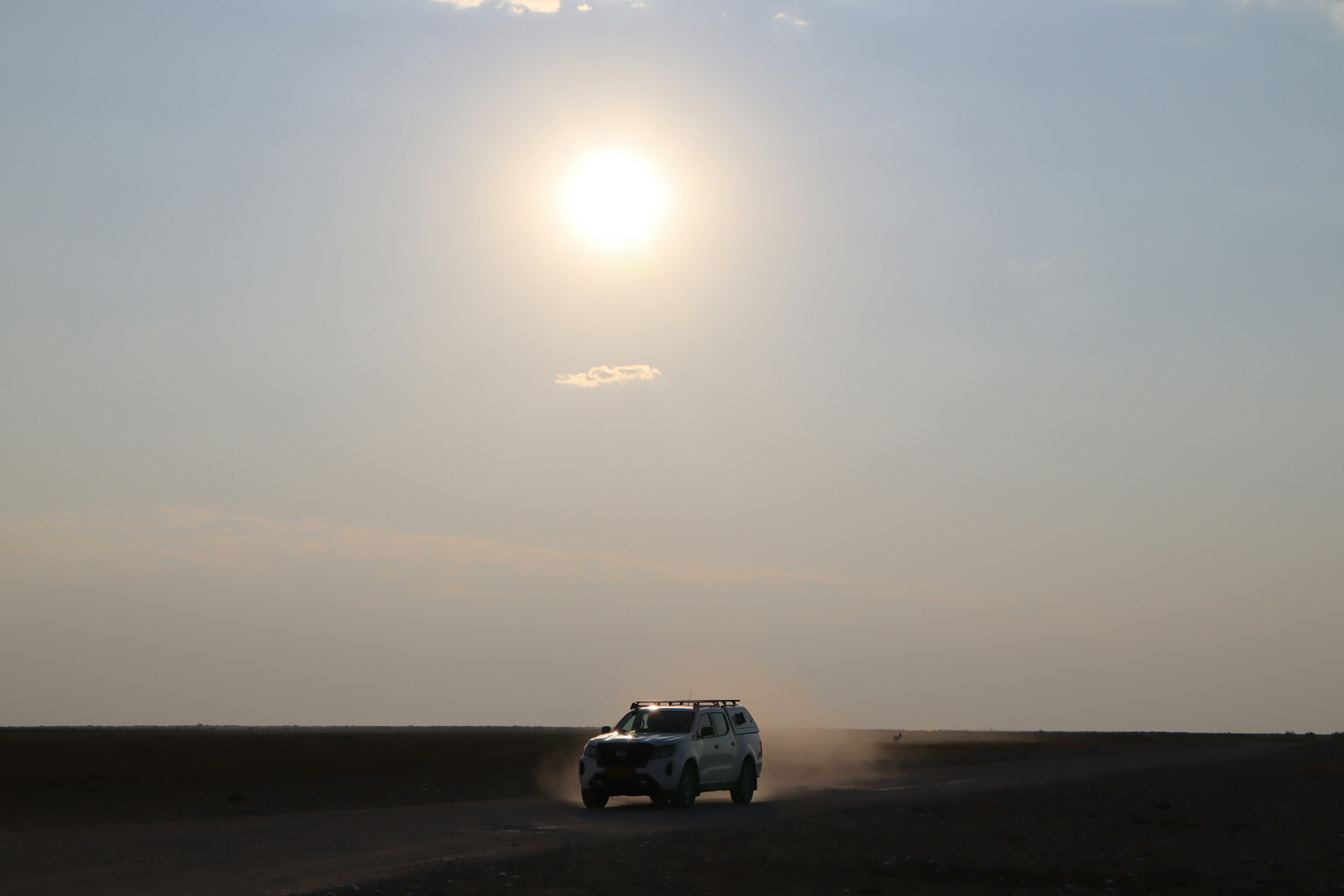 White SUV driving on a road under a bright sun