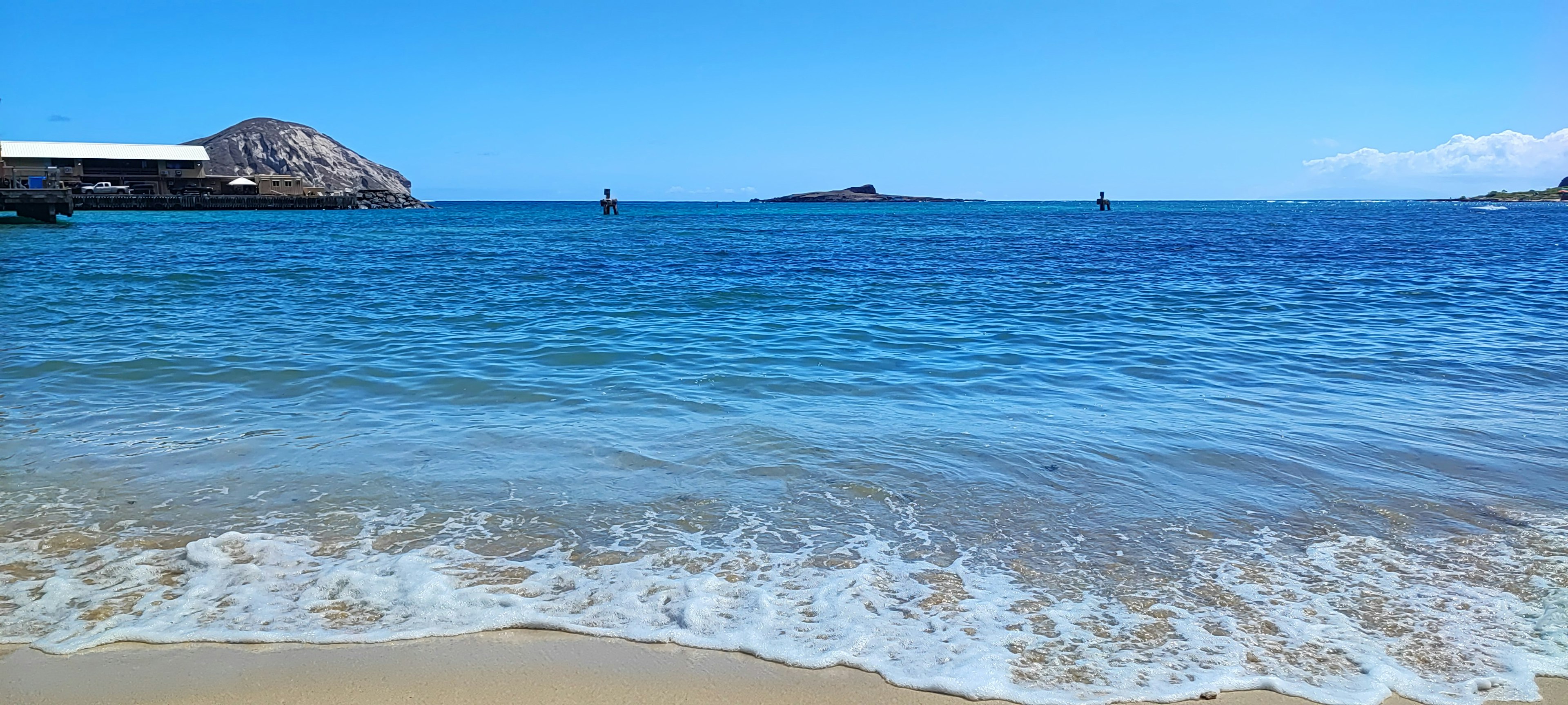 Vista escénica del océano azul y la playa de arena con islas distantes