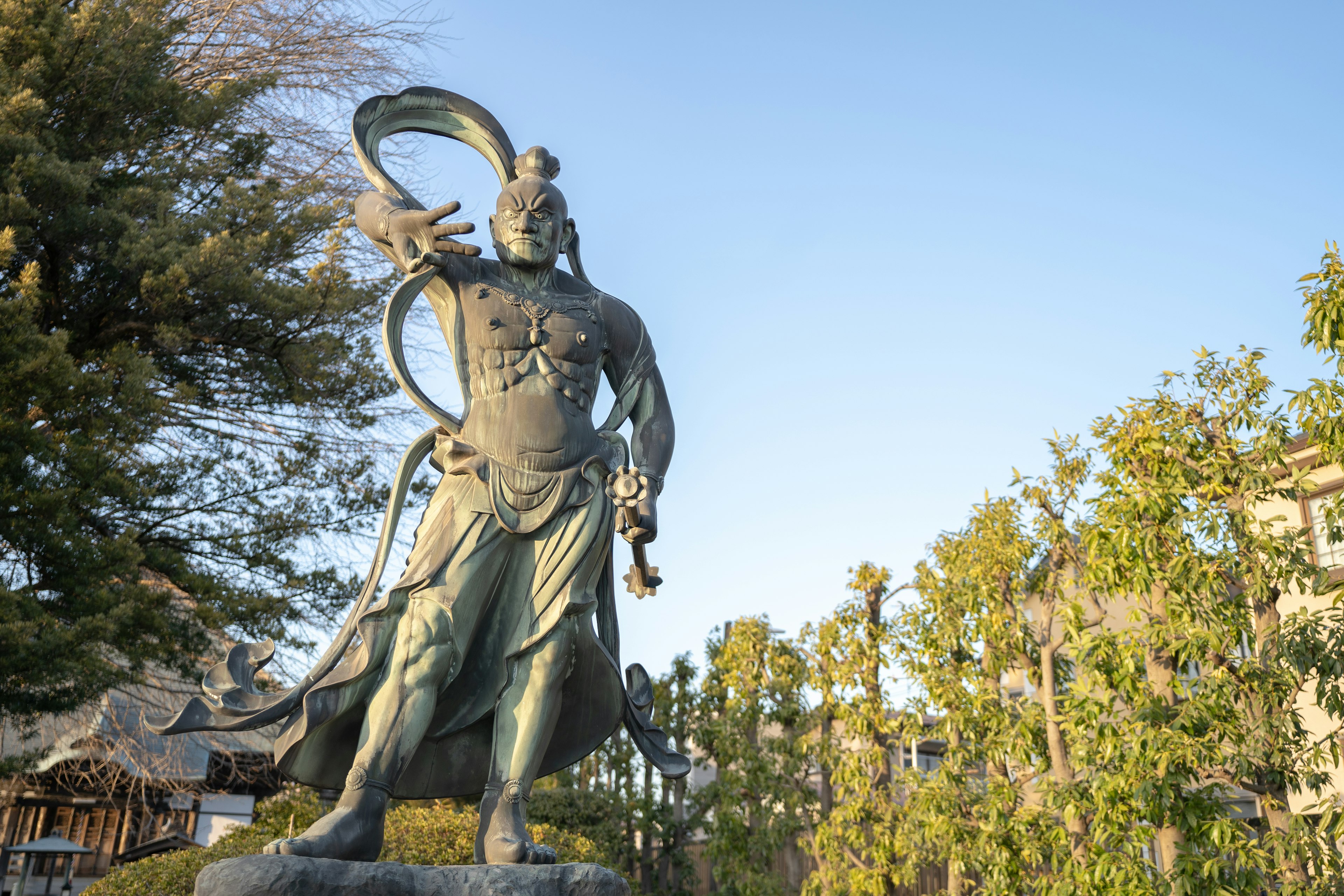 Eine majestätische Statue, die unter einem blauen Himmel steht und eine Schlange in der Hand hält