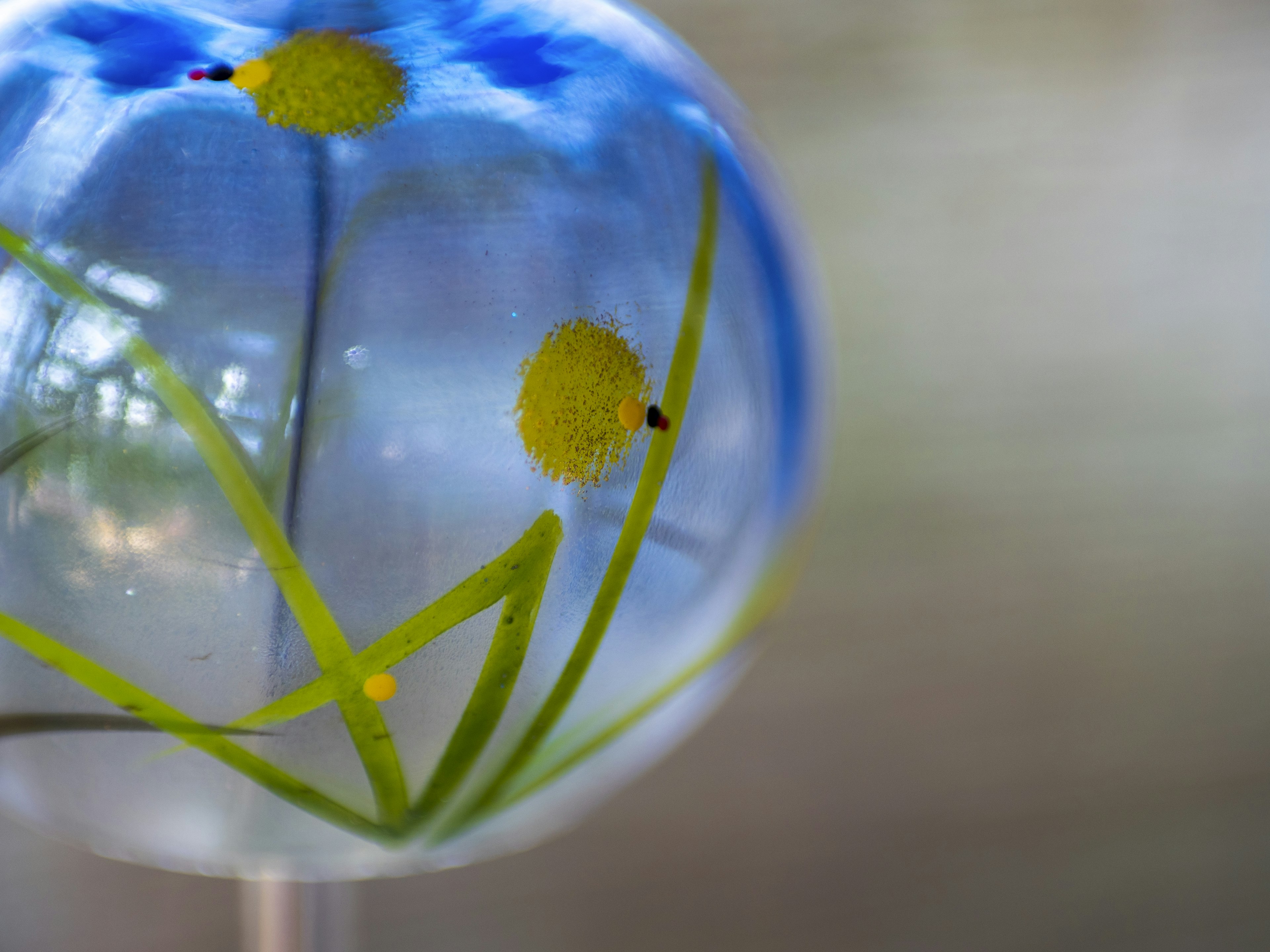 Transparent glass ball with yellow flower design against a blue background