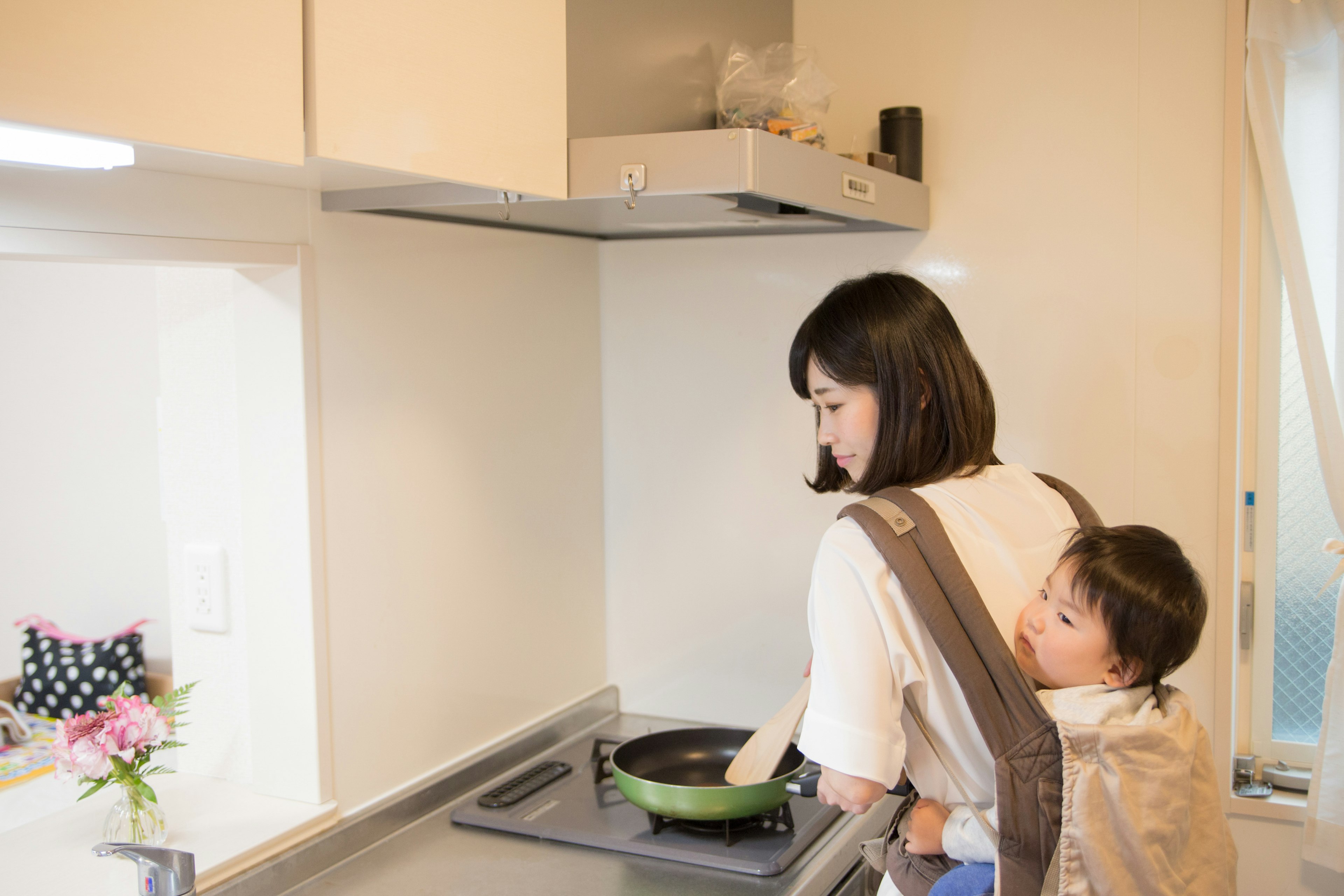 Una madre che cucina in cucina con un bambino sulla schiena