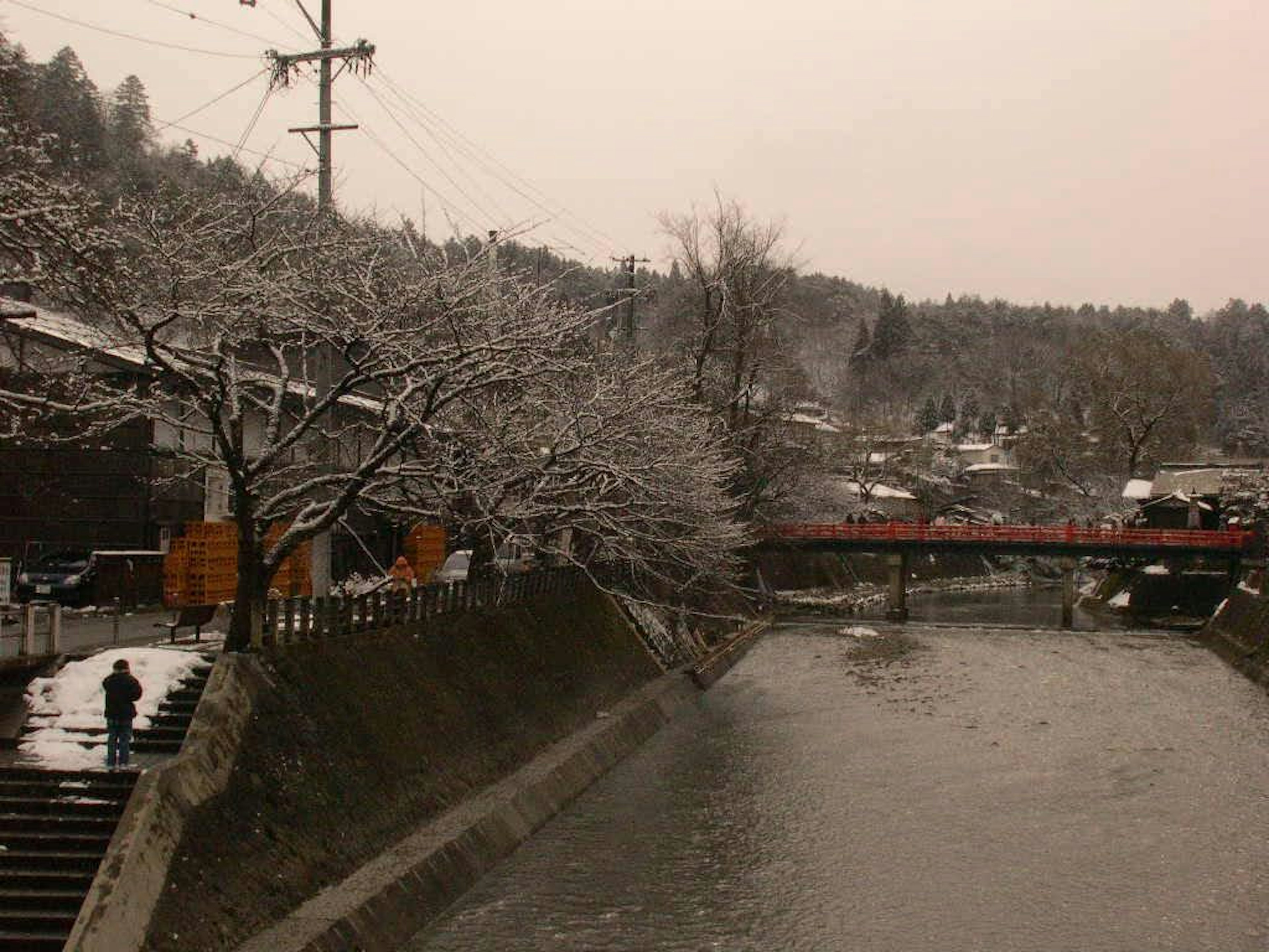 Escena de río cubierto de nieve con un puente rojo