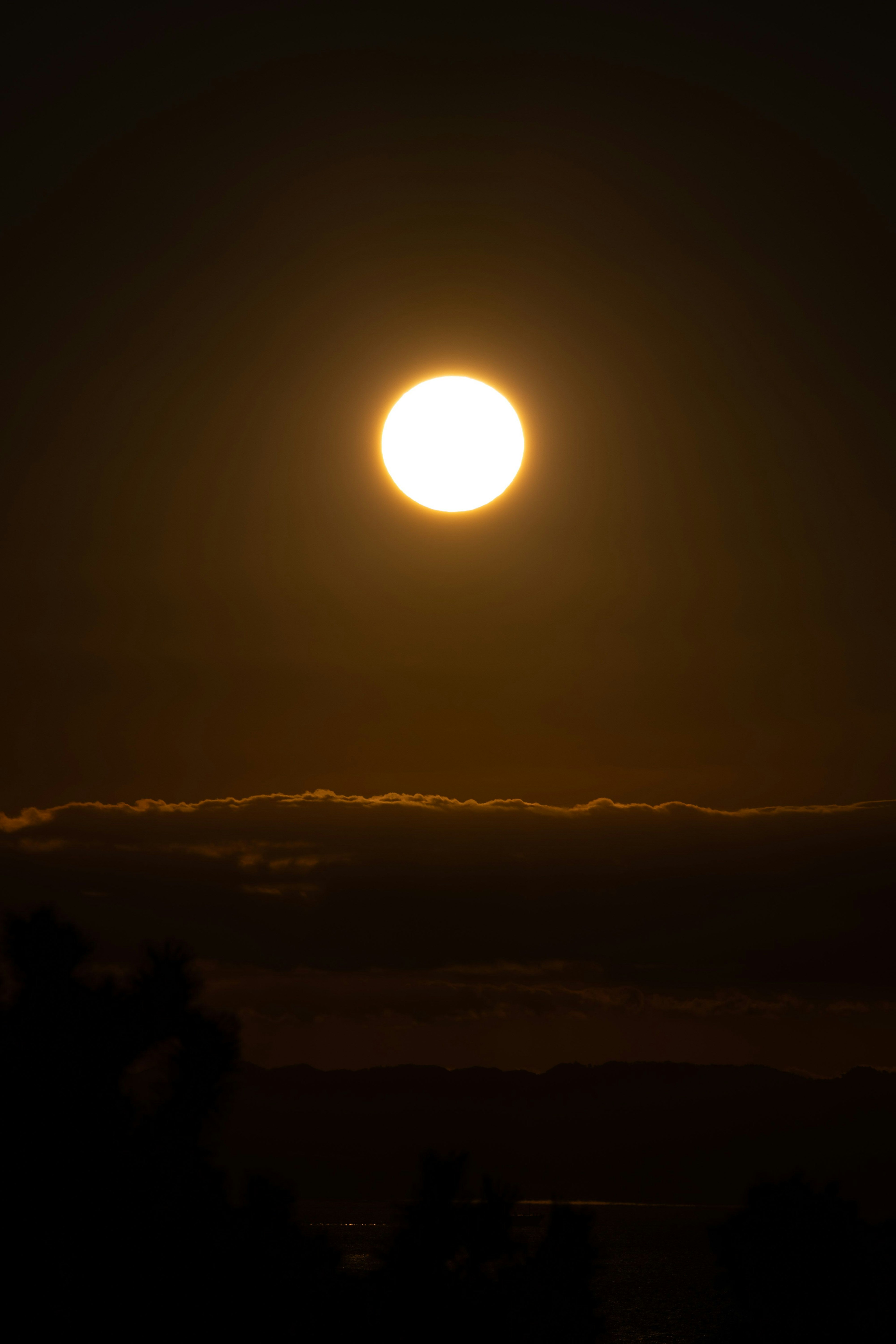 夕日が雲の上に輝いているシルエットの画像