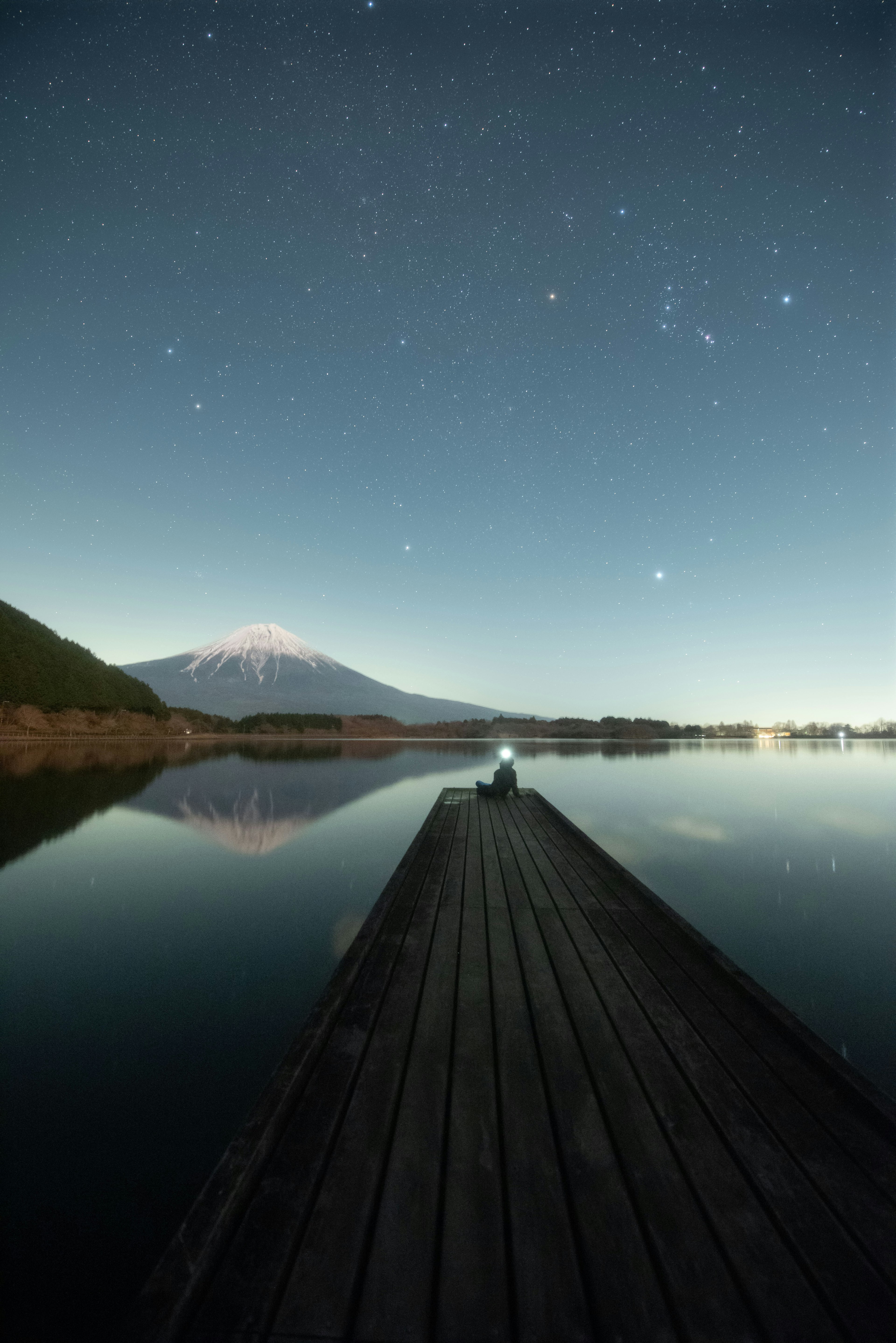 静かな湖の上に広がる星空と富士山の美しい風景