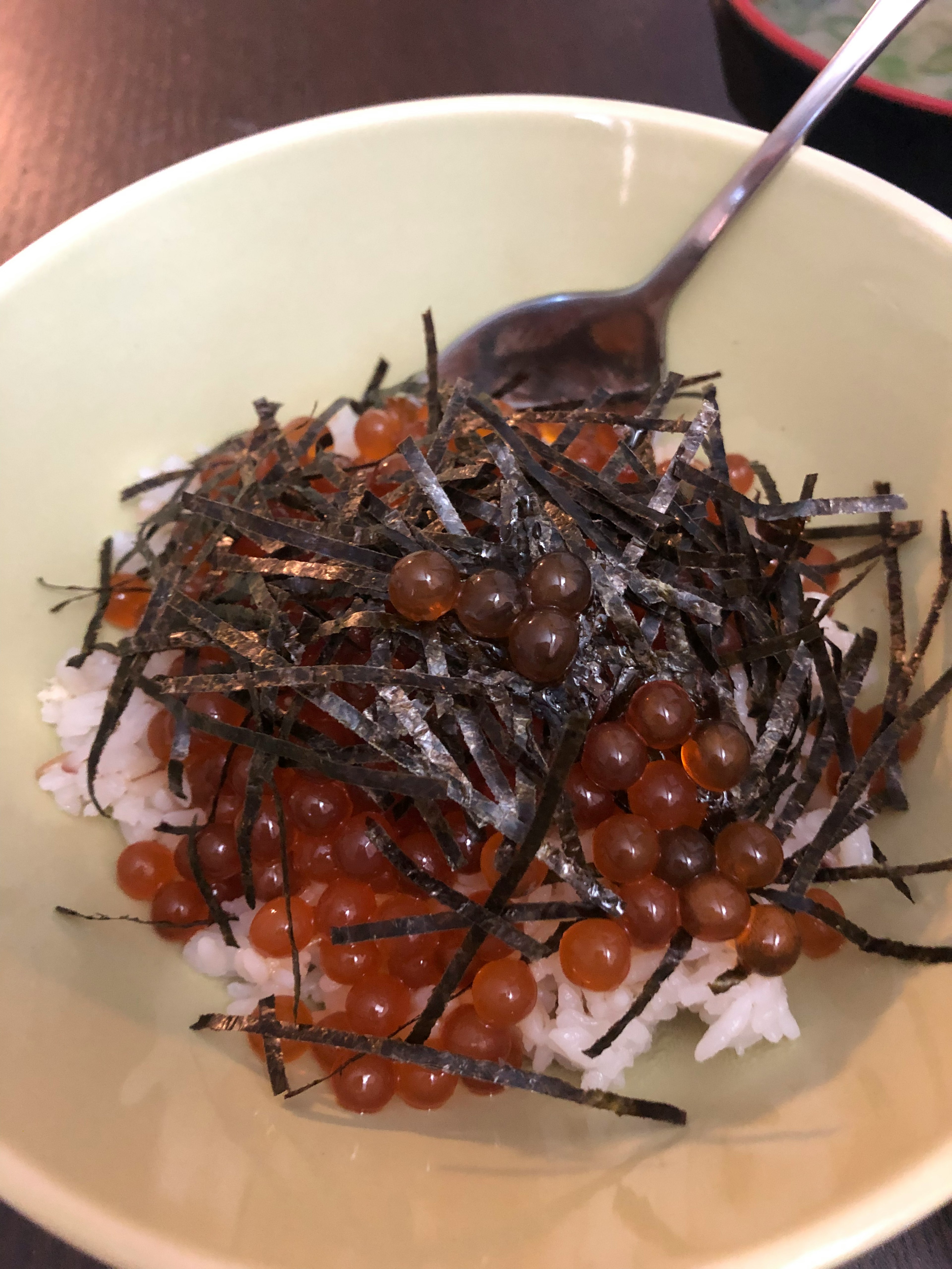 Un tazón de arroz cubierto con huevas de salmón y alga