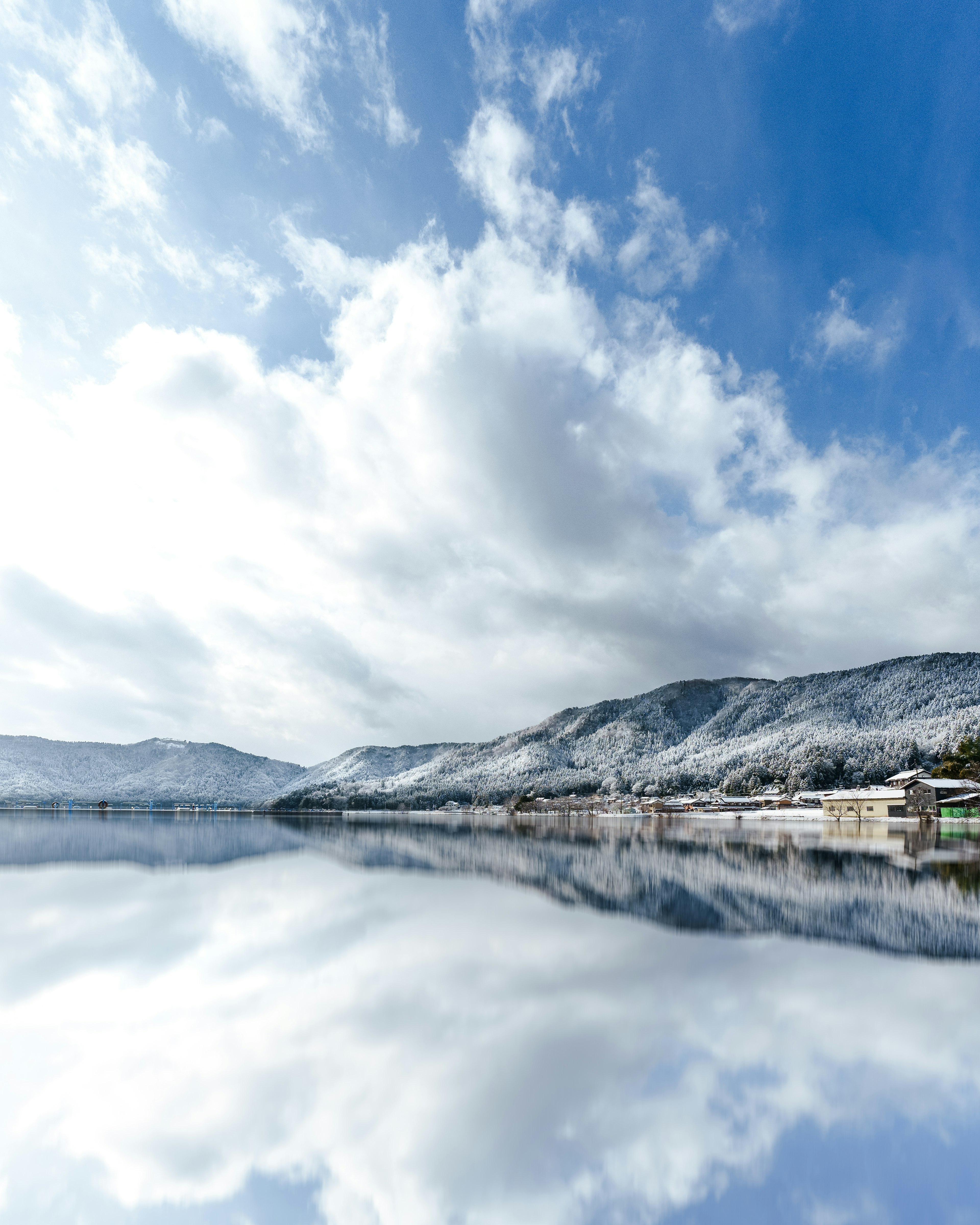 雪に覆われた山々と青い空が映る静かな湖の風景