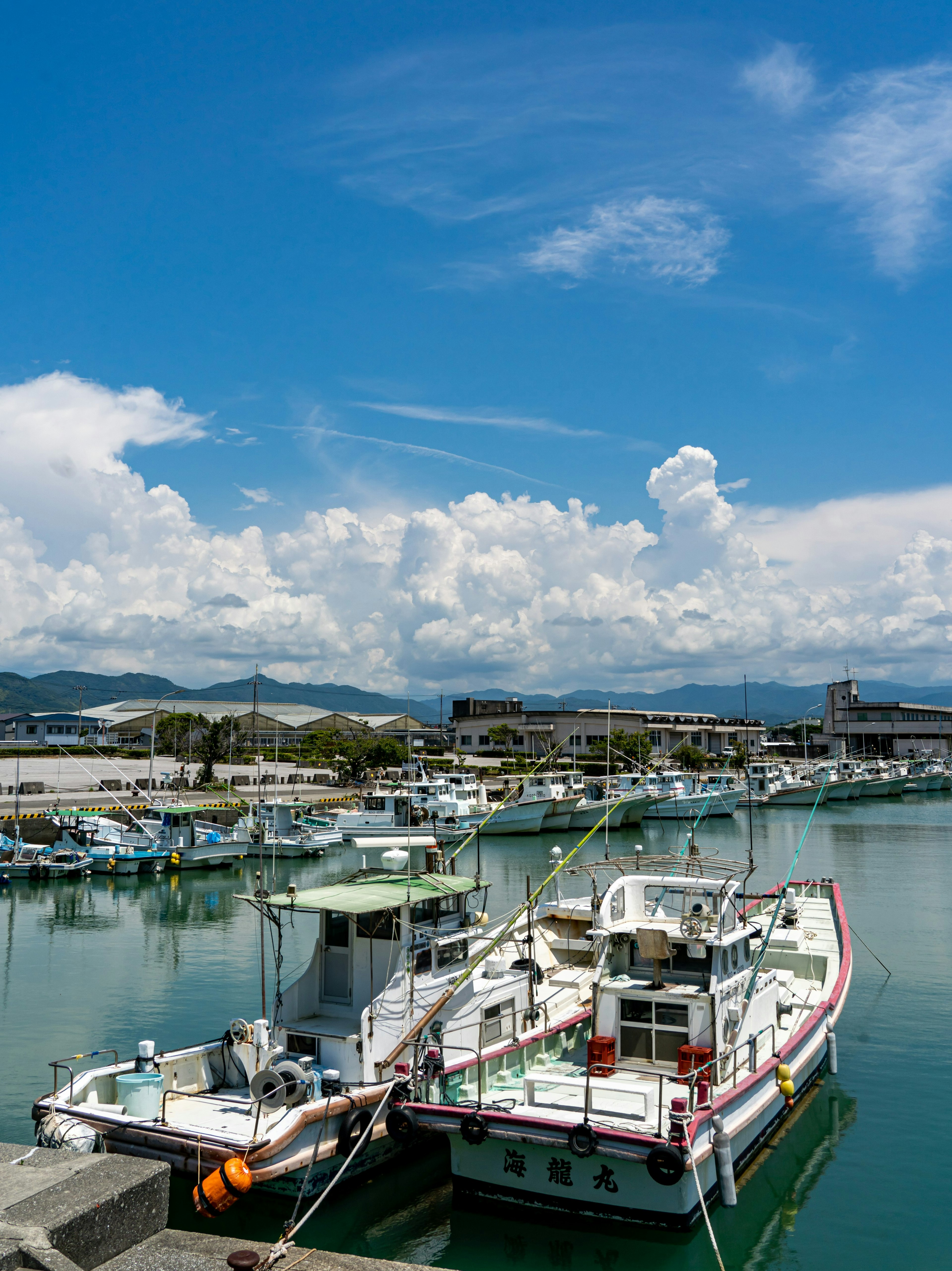 Bateaux de pêche amarrés dans un port sous un ciel bleu avec des nuages blancs