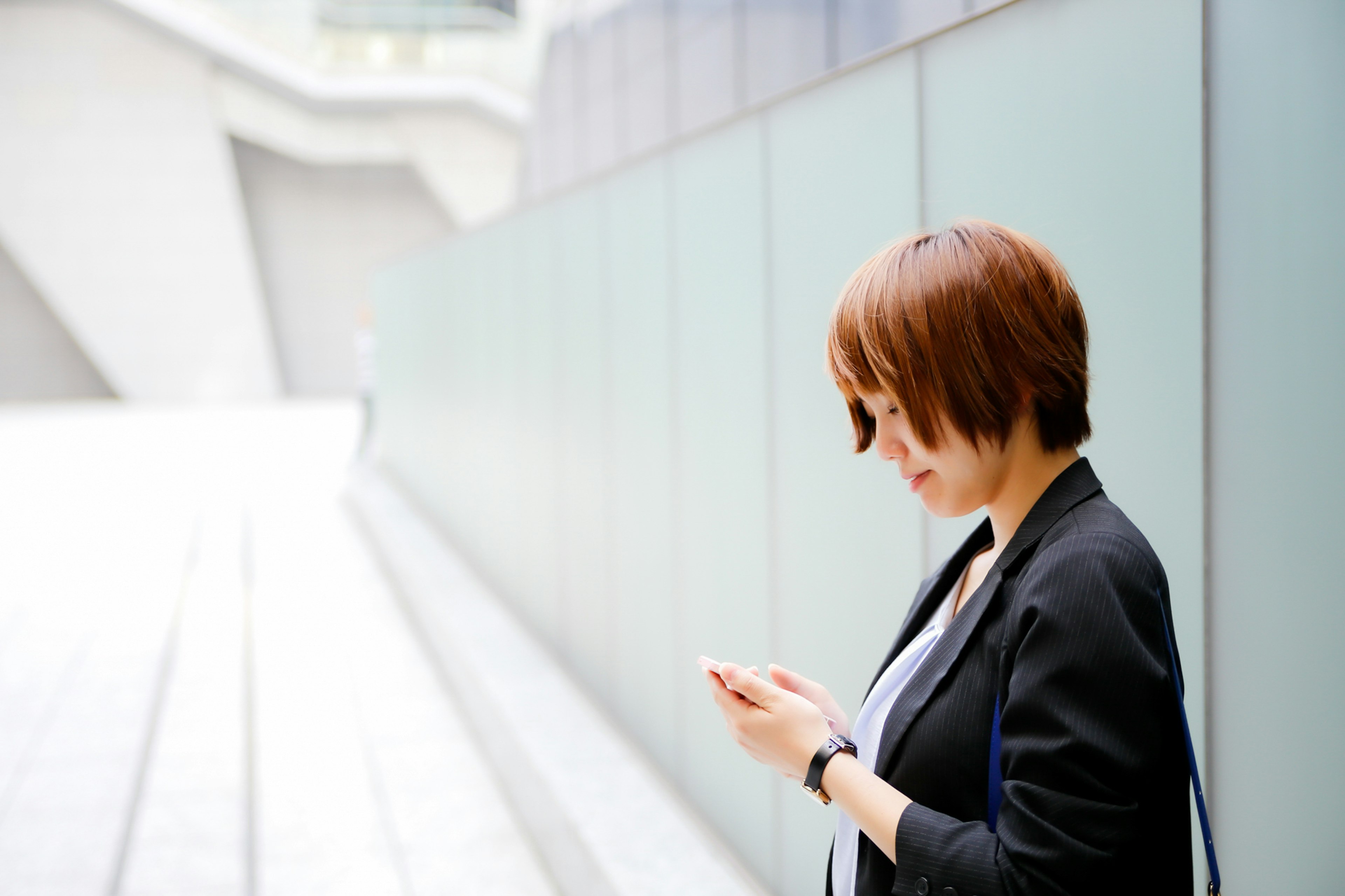 Mujer mirando su smartphone en un entorno arquitectónico moderno