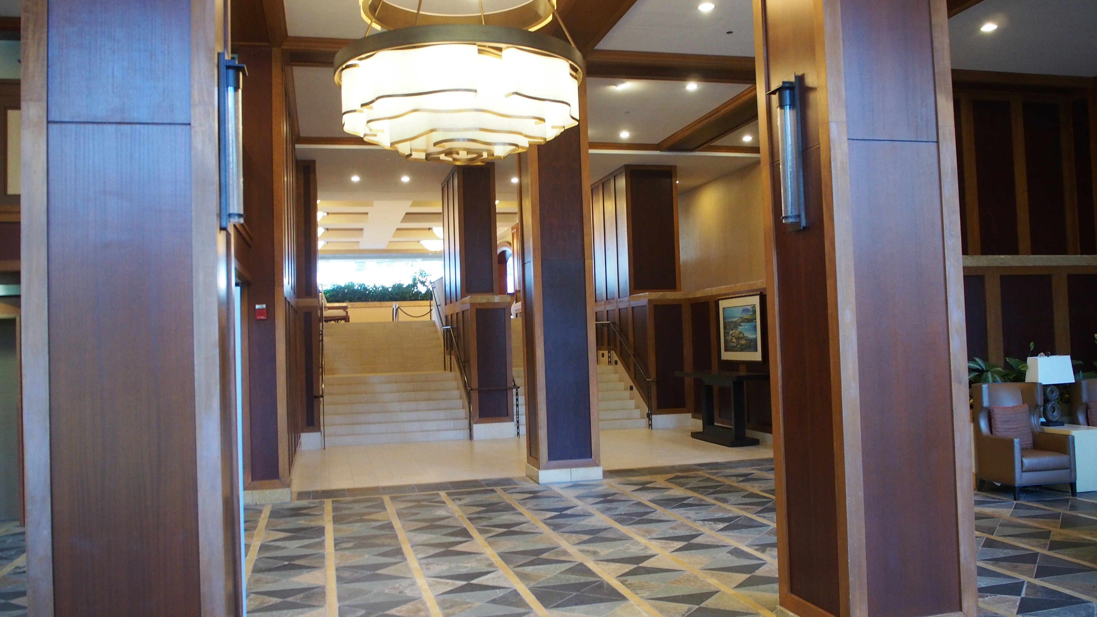 Luxurious lobby interior with chandelier and wooden pillars featuring staircase