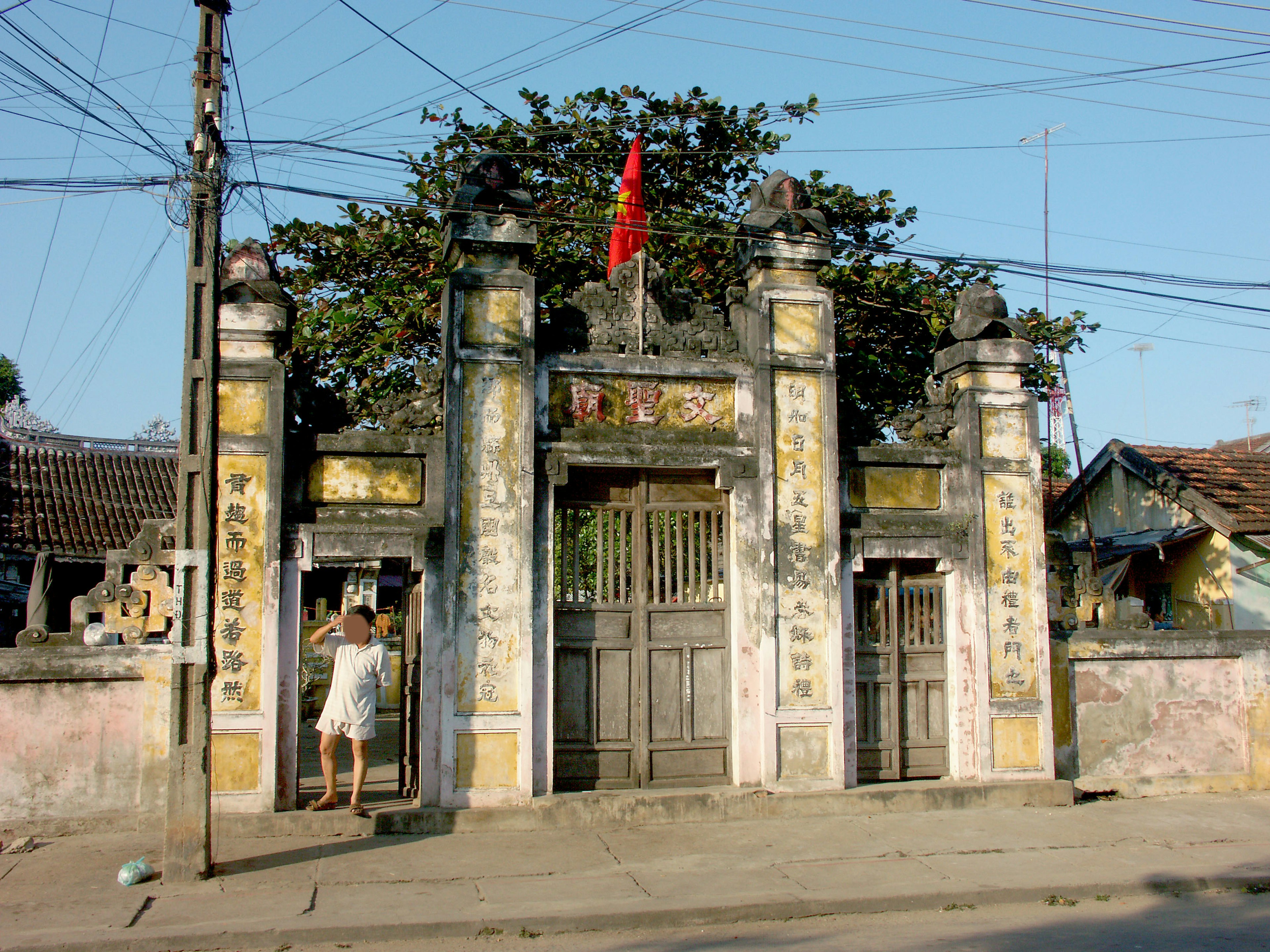 An old gate with a red flag and power lines in the background