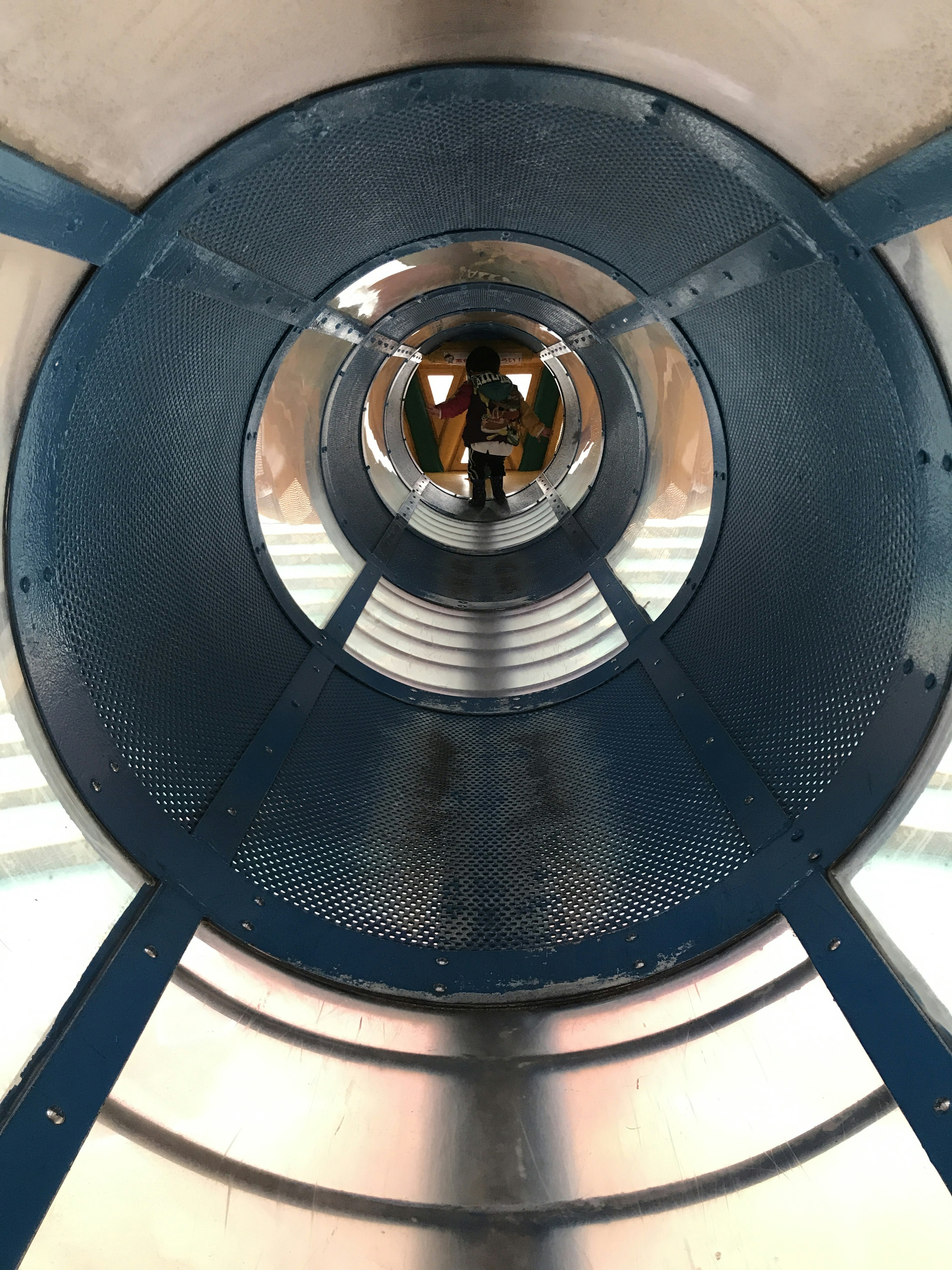 View of the interior of a blue tunnel with a person visible at the center