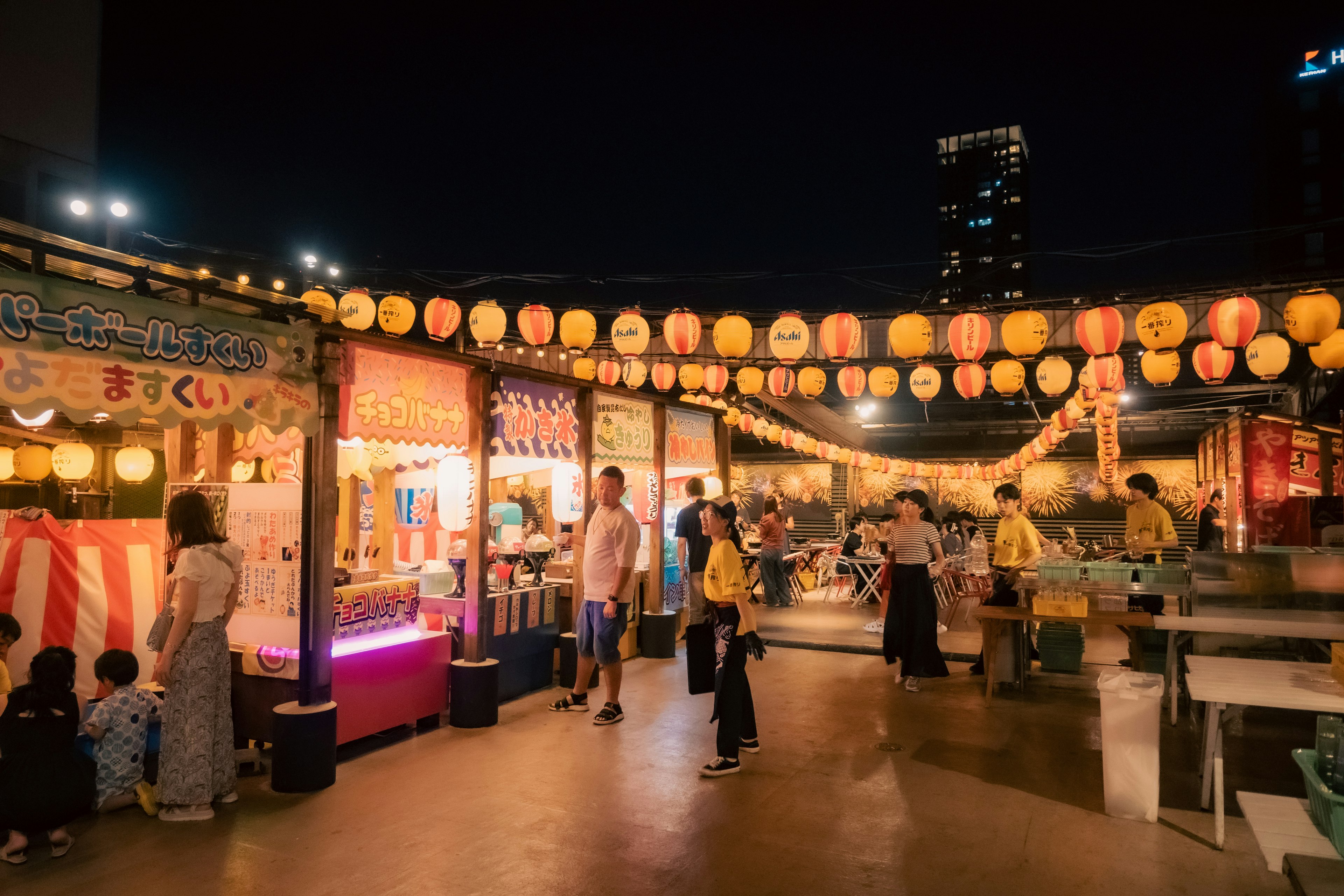 Pemandangan festival yang meriah dengan stan makanan dan lentera yang diterangi di malam hari