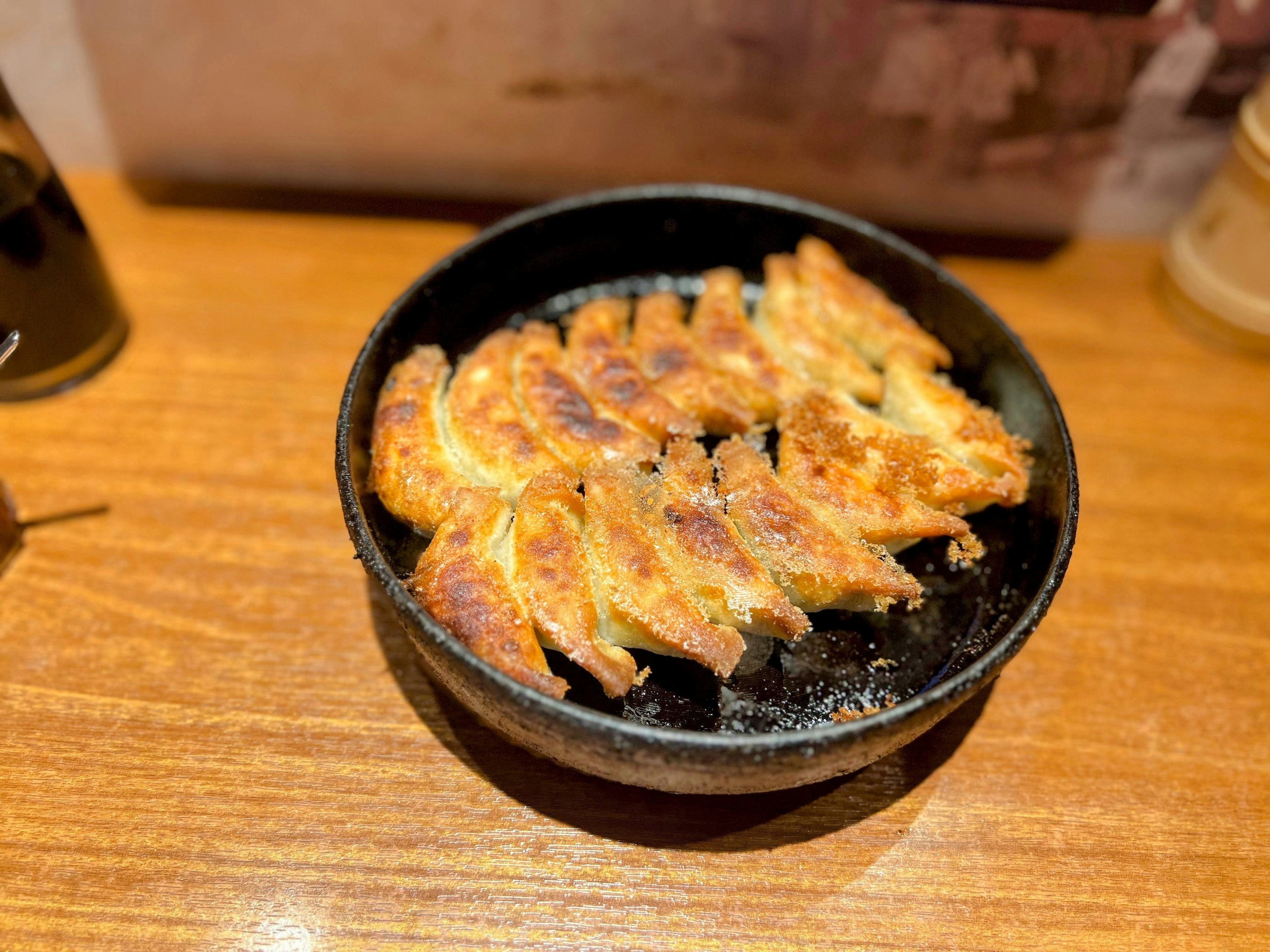 Fried gyoza arranged in a black bowl