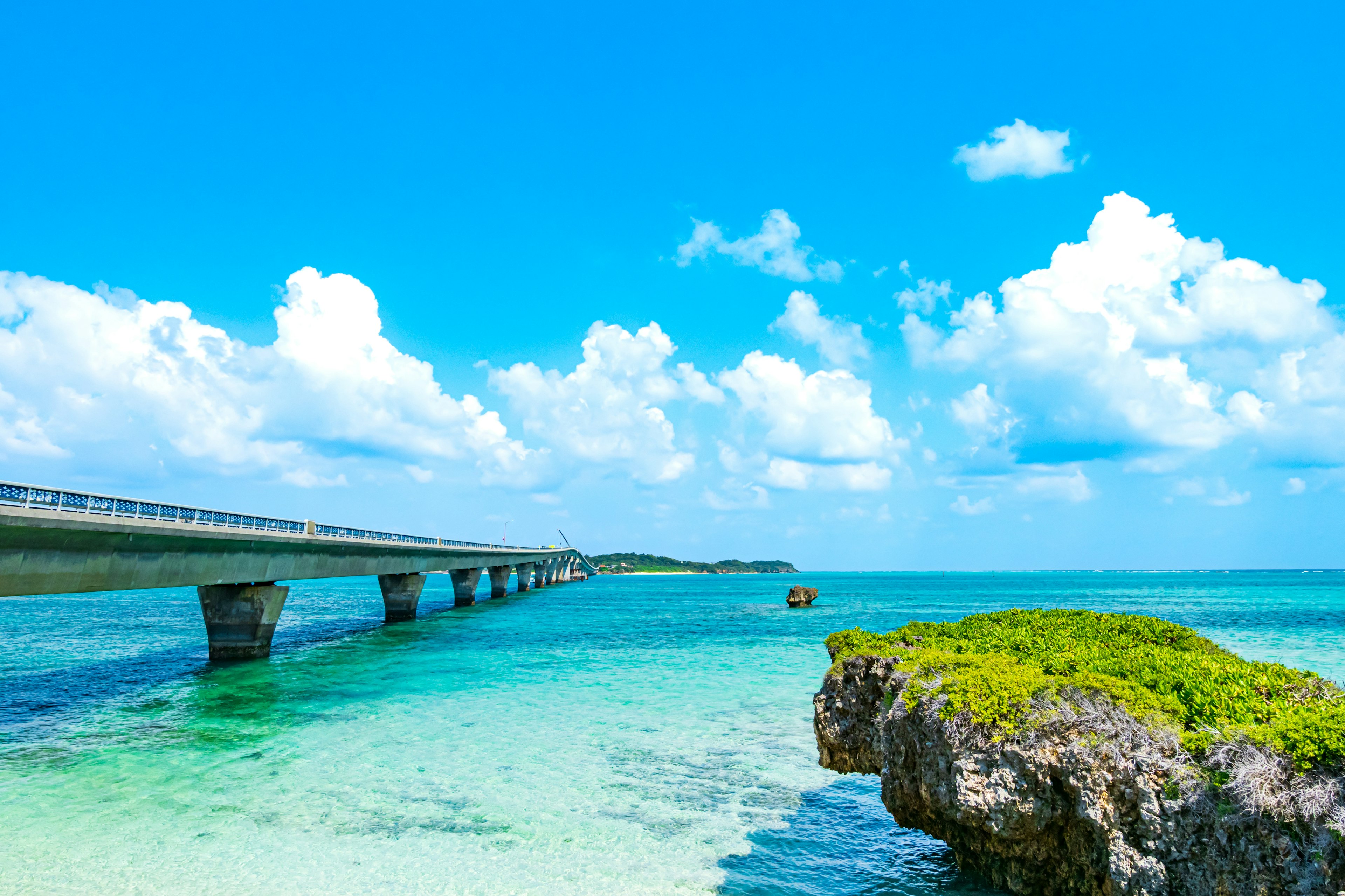 Vista escénica de un puente sobre aguas turquesas con cielo azul brillante y nubes esponjosas