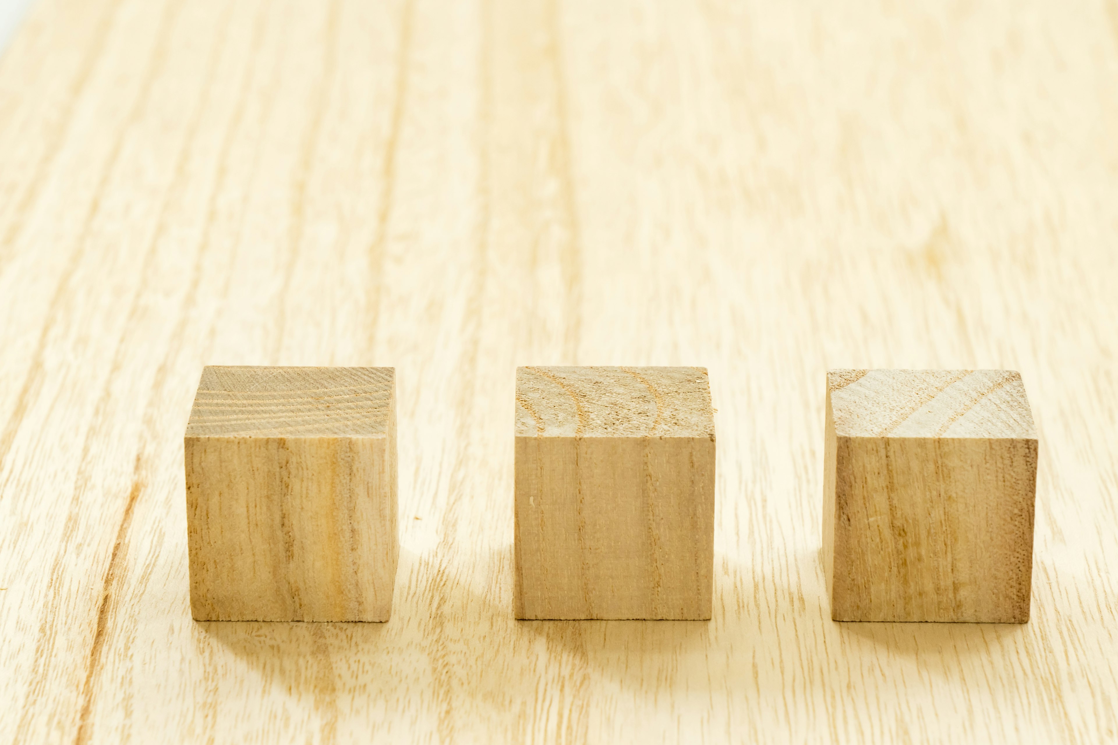 Trois cubes en bois disposés sur une surface en bois clair