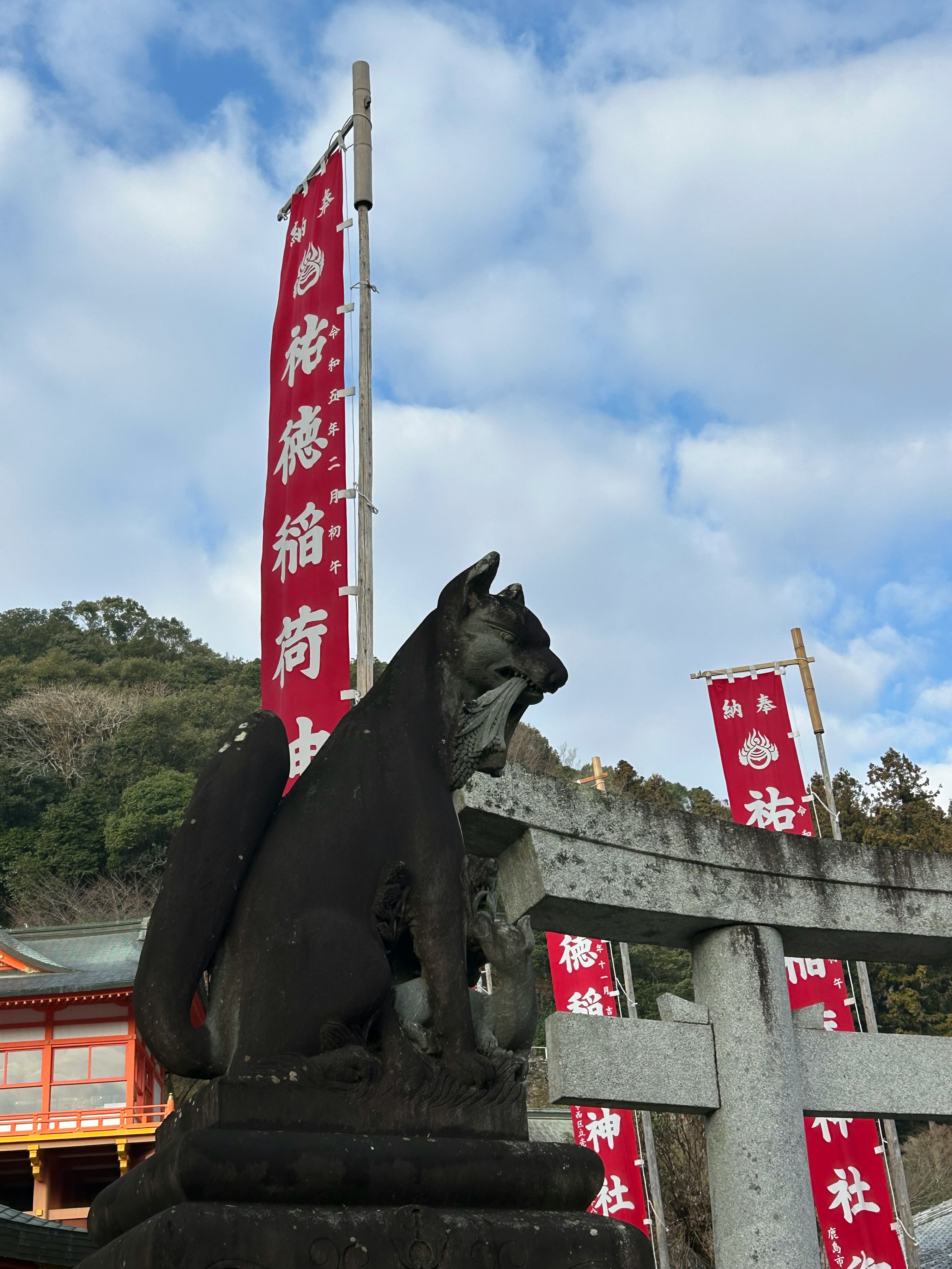 Stone guardian dog at a shrine with red banners in the background